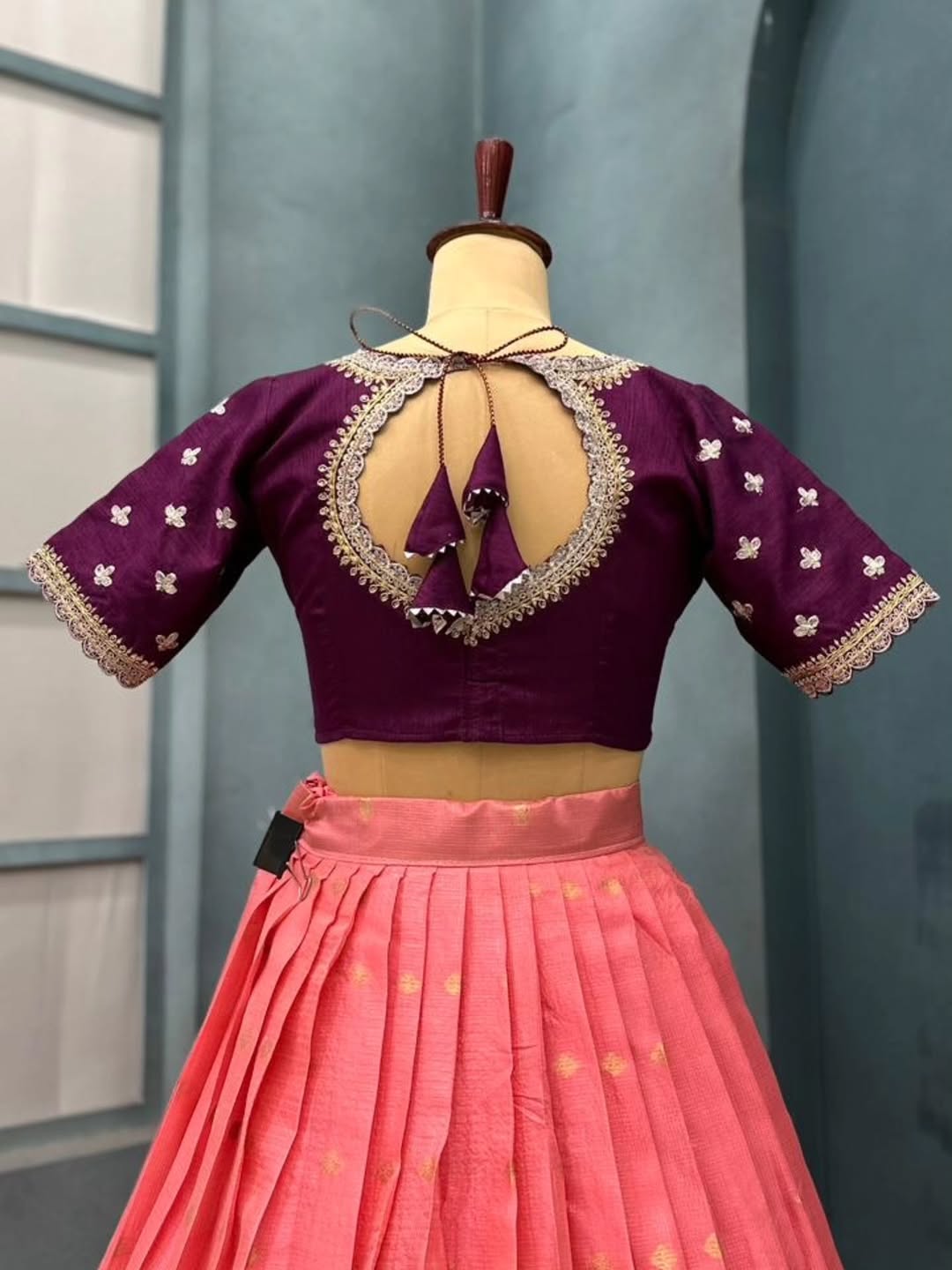 Peach lehanga with intricate designs on a mannequin against a plain background