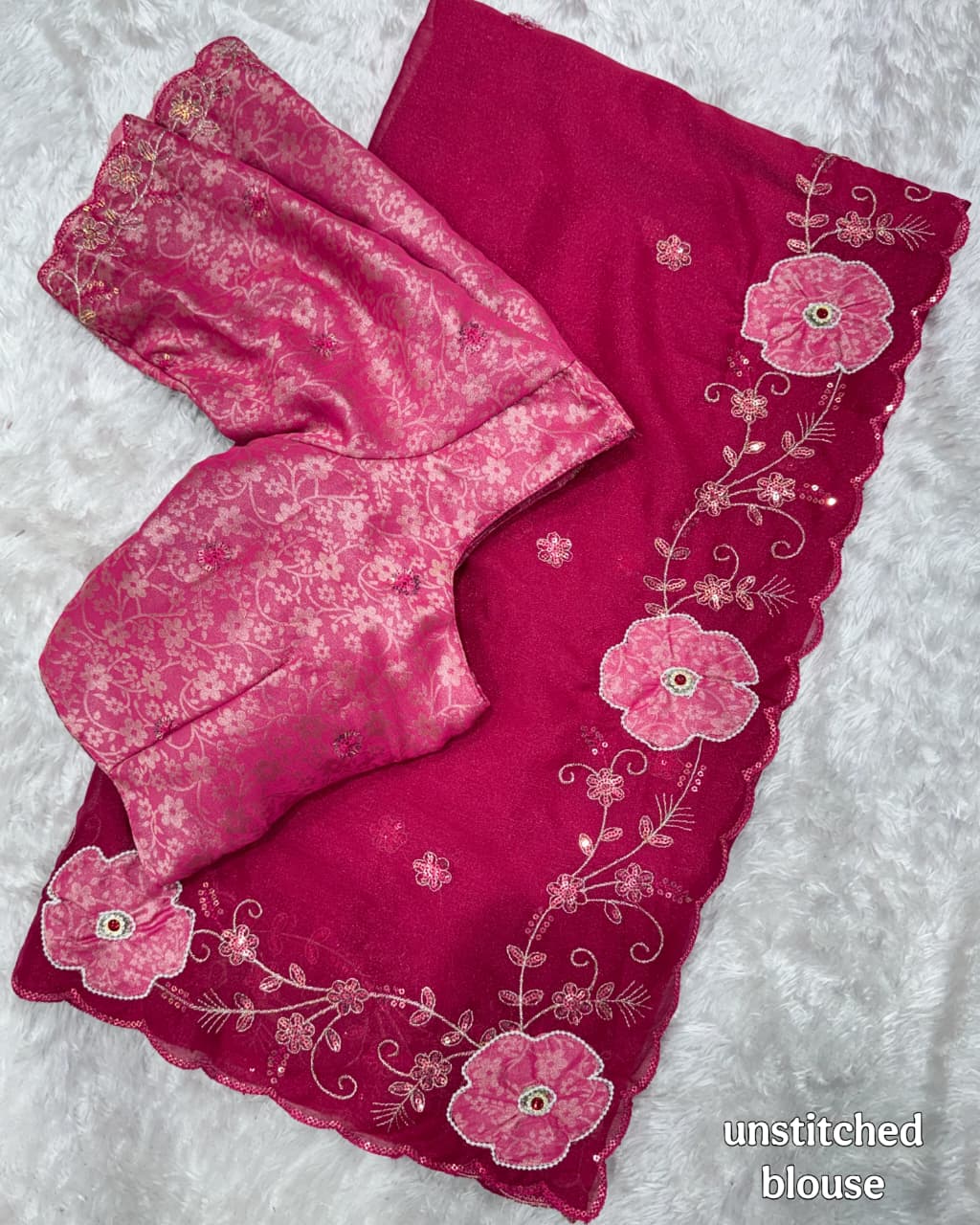 Pink saree and unstitched blouse with floral embroidery on a white background