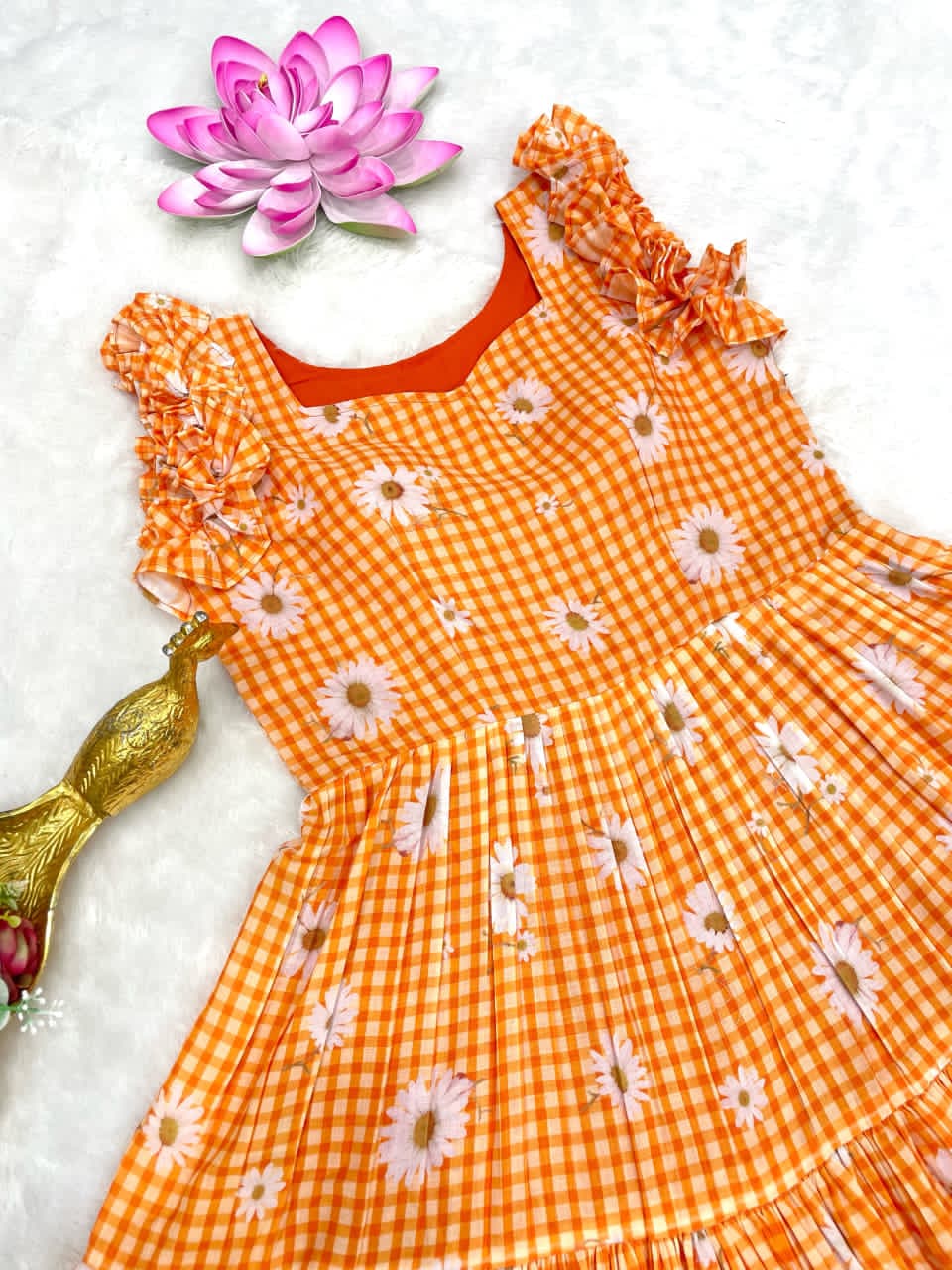 Orange checkered dress with white floral patterns and matching headband on a light background