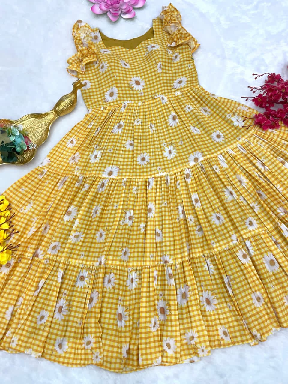 Yellow floral dress on a white background with decorative elements.