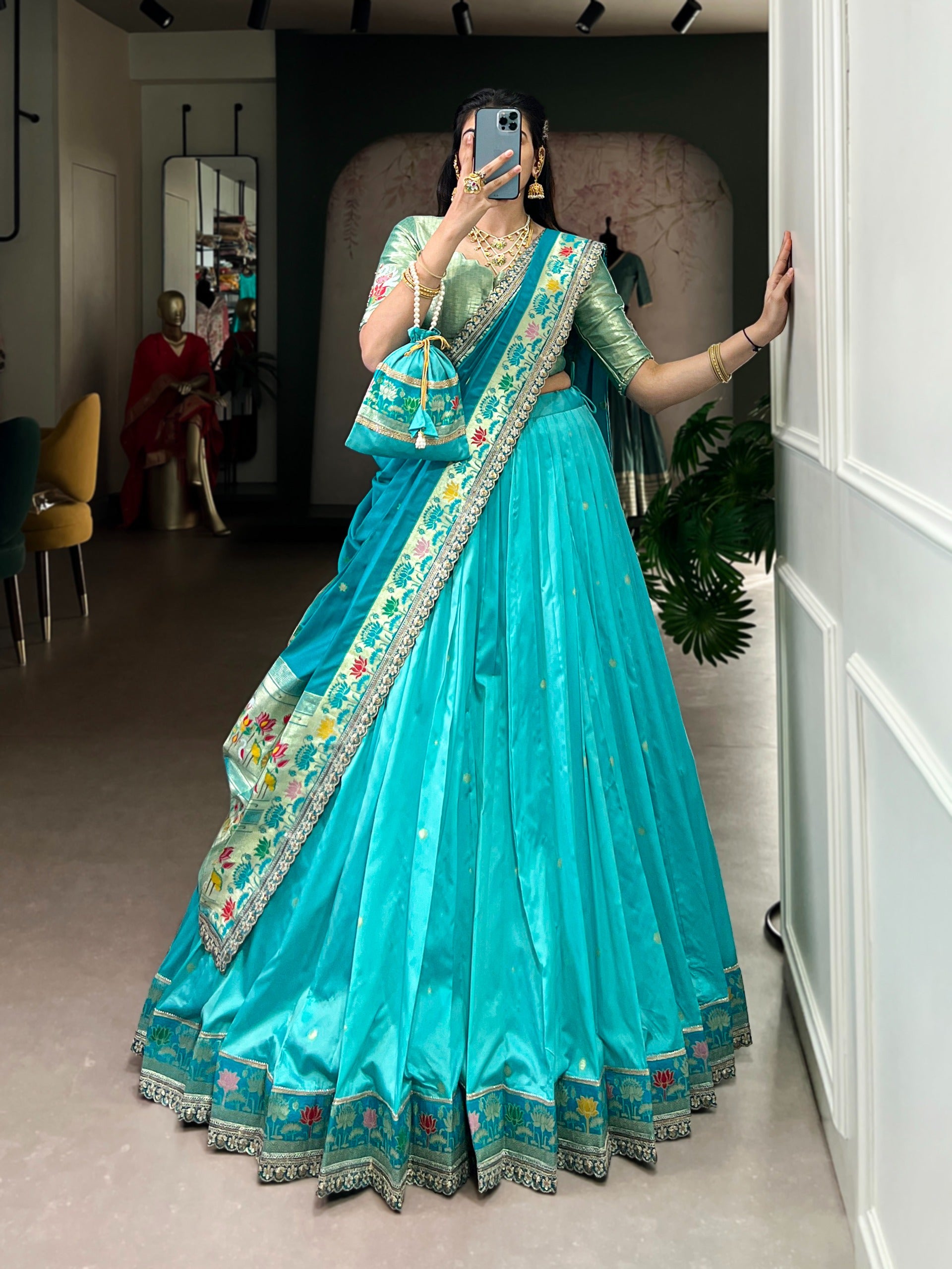 Person wearing a traditional sky blue saree with gold embroidery in a room.