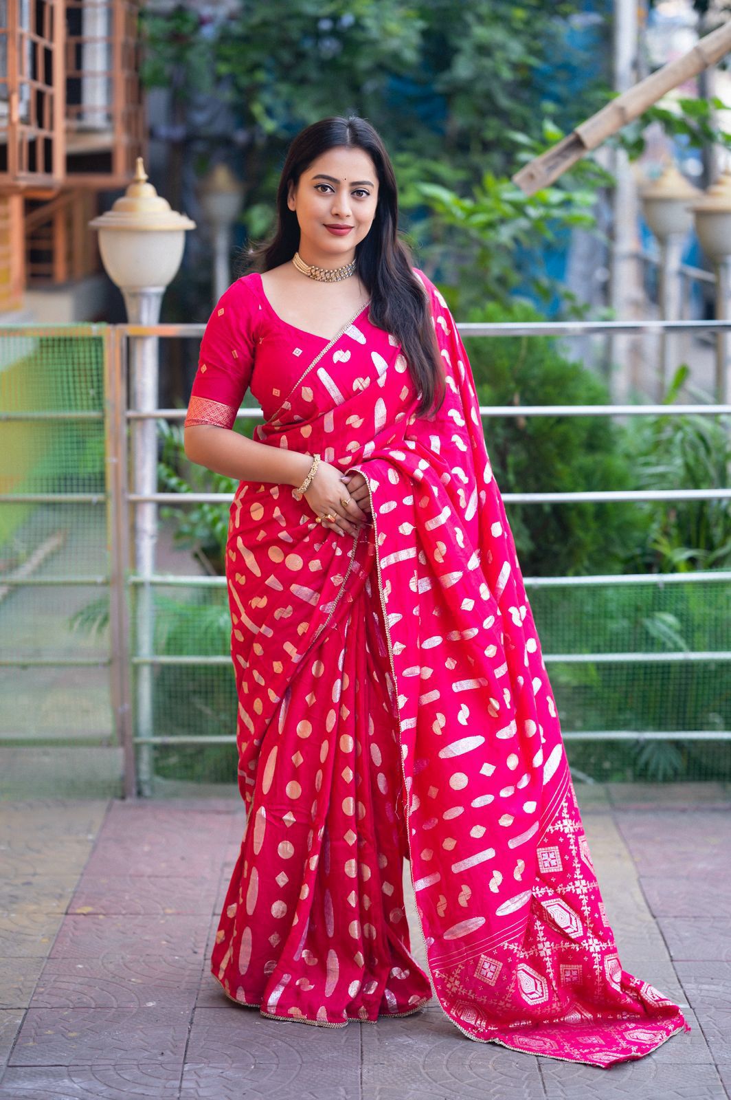 Woman wearing a pink saree with white patterns outdoors