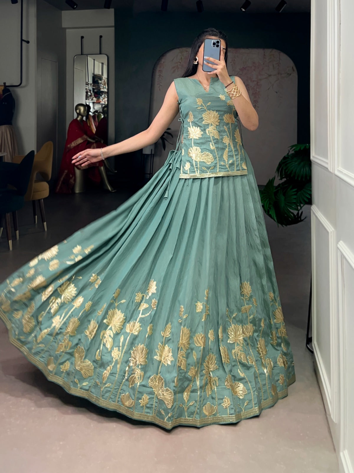 Sea green traditional outfit with gold embroidery in a room.