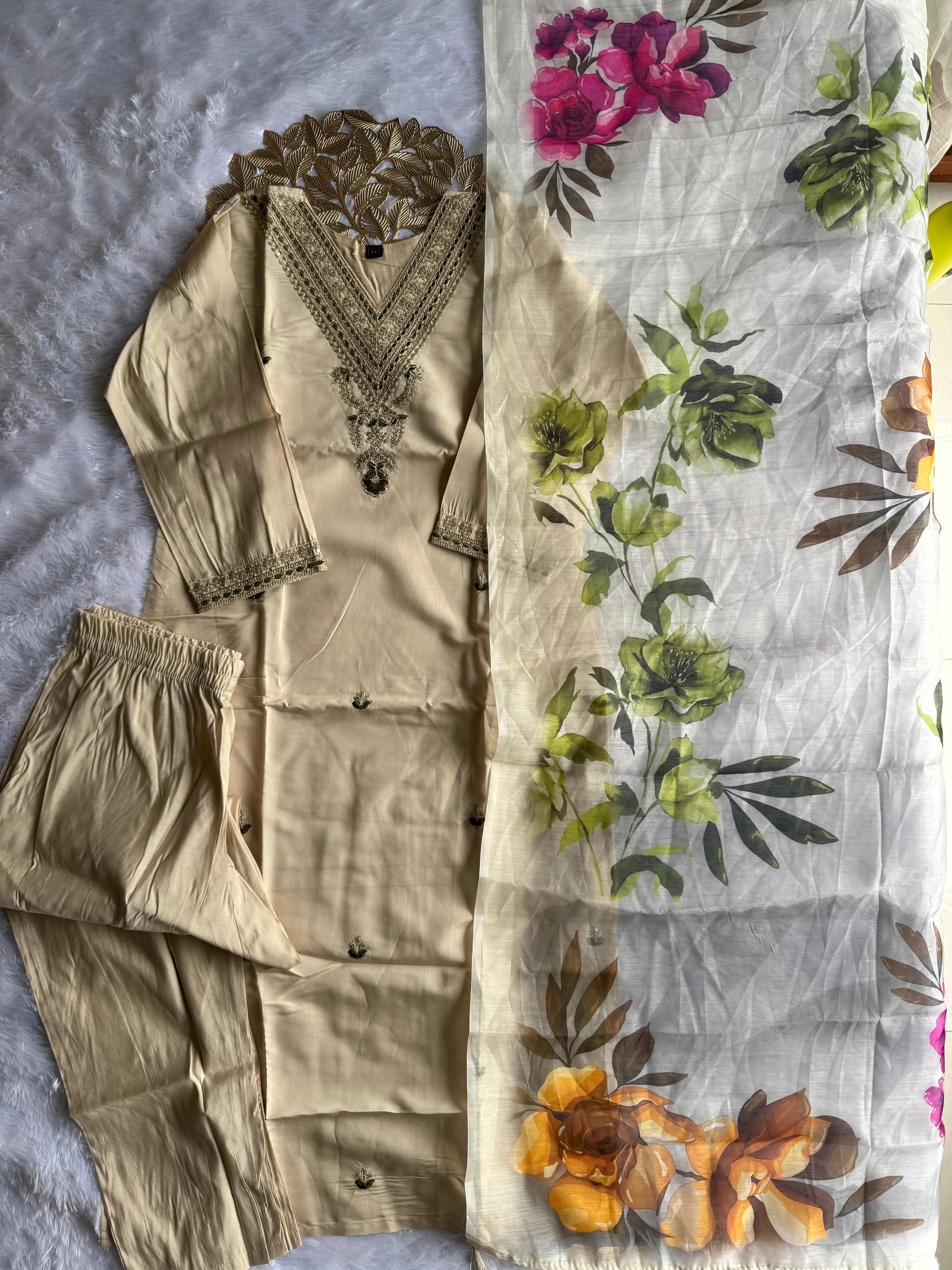 Beige traditional outfit with embroidered top and pants on a floral fabric background