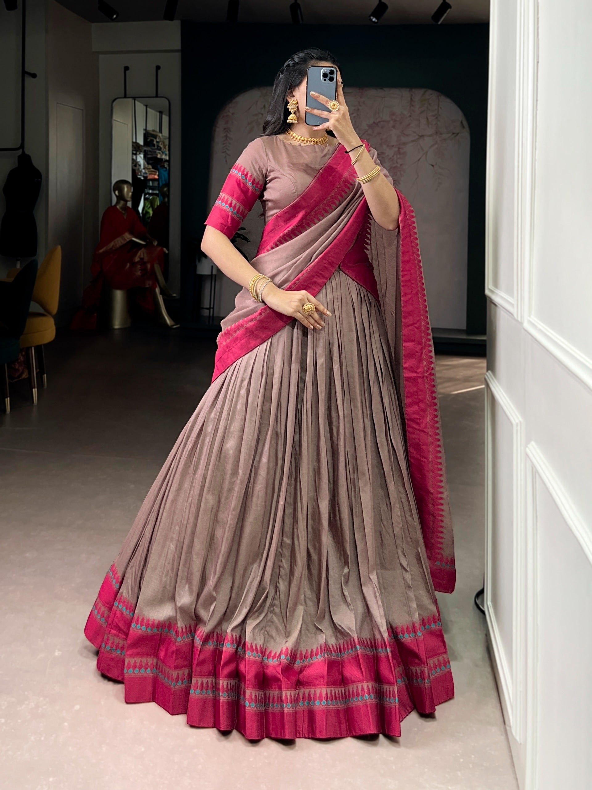 Woman wearing a copper saree taking a mirror selfie.