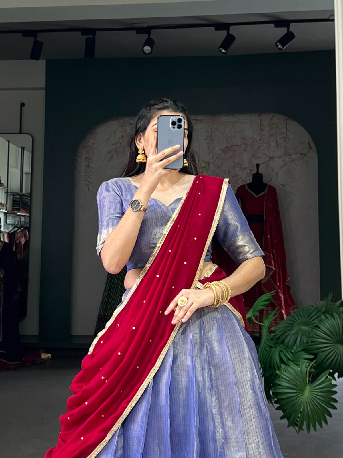 Lavender saree with a red border, taking a mirror selfie.