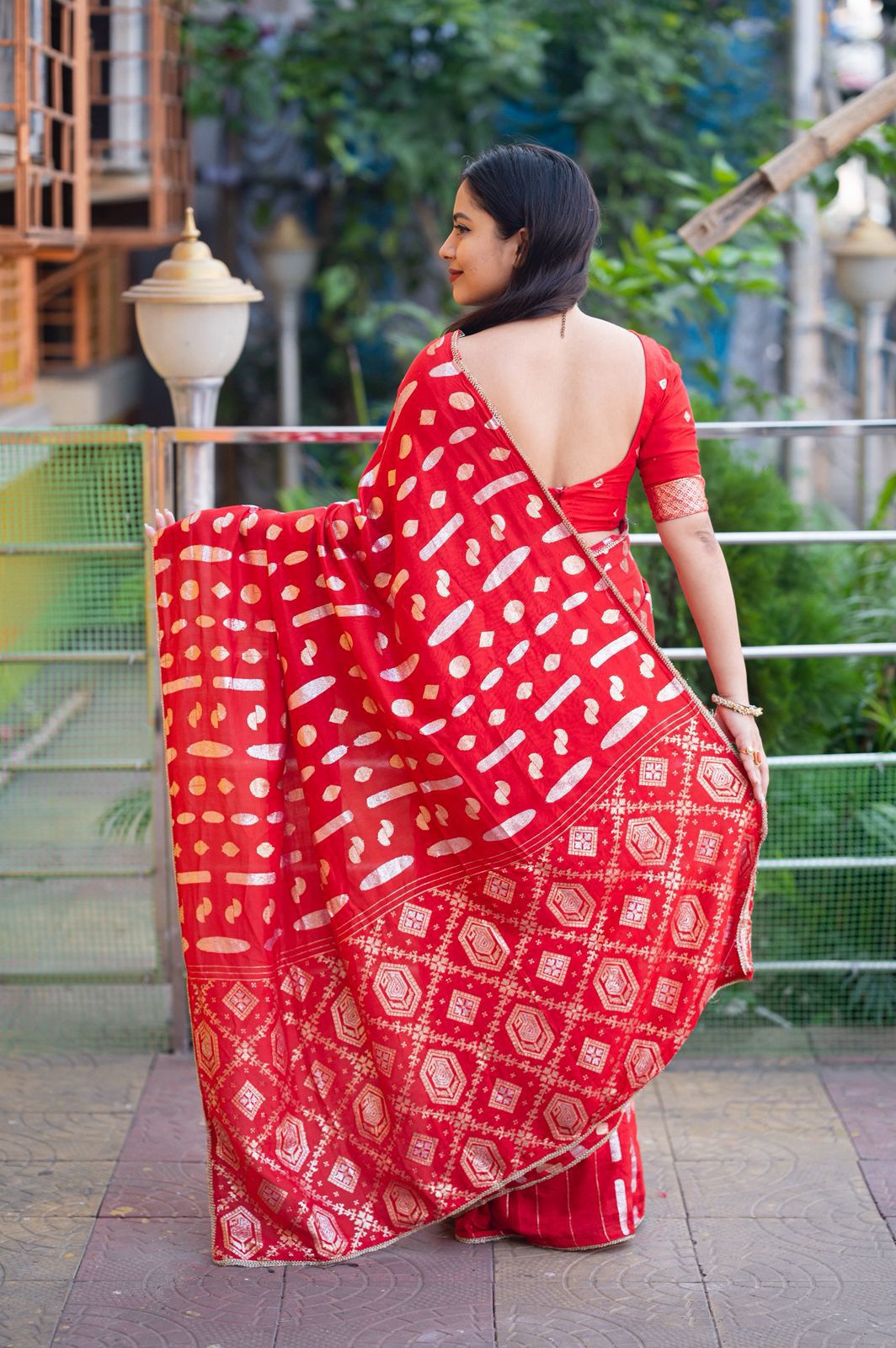 Woman wearing a red saree with white patterns outdoors