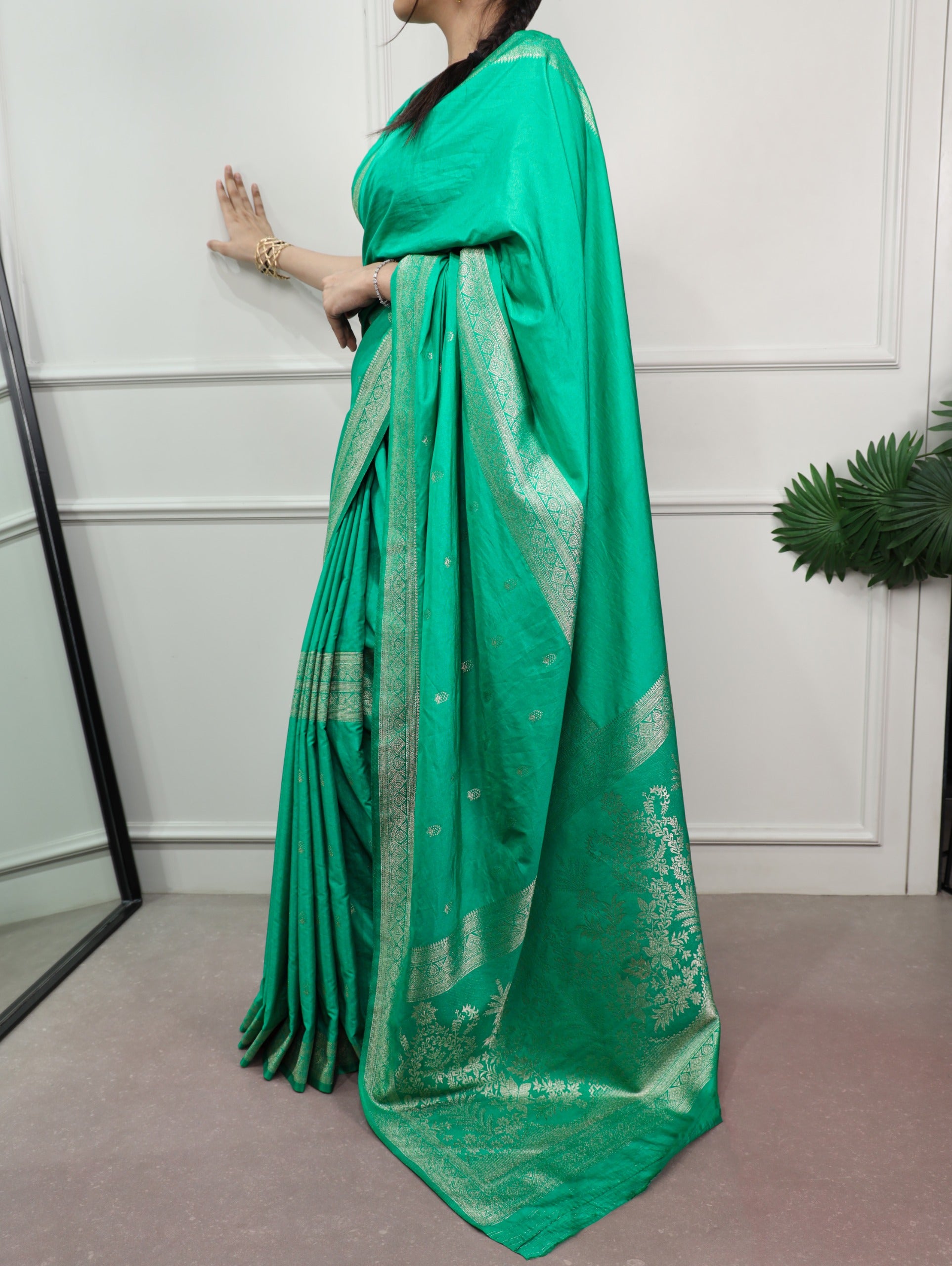 Cyan saree with white patterns draped over a person against a white wall.