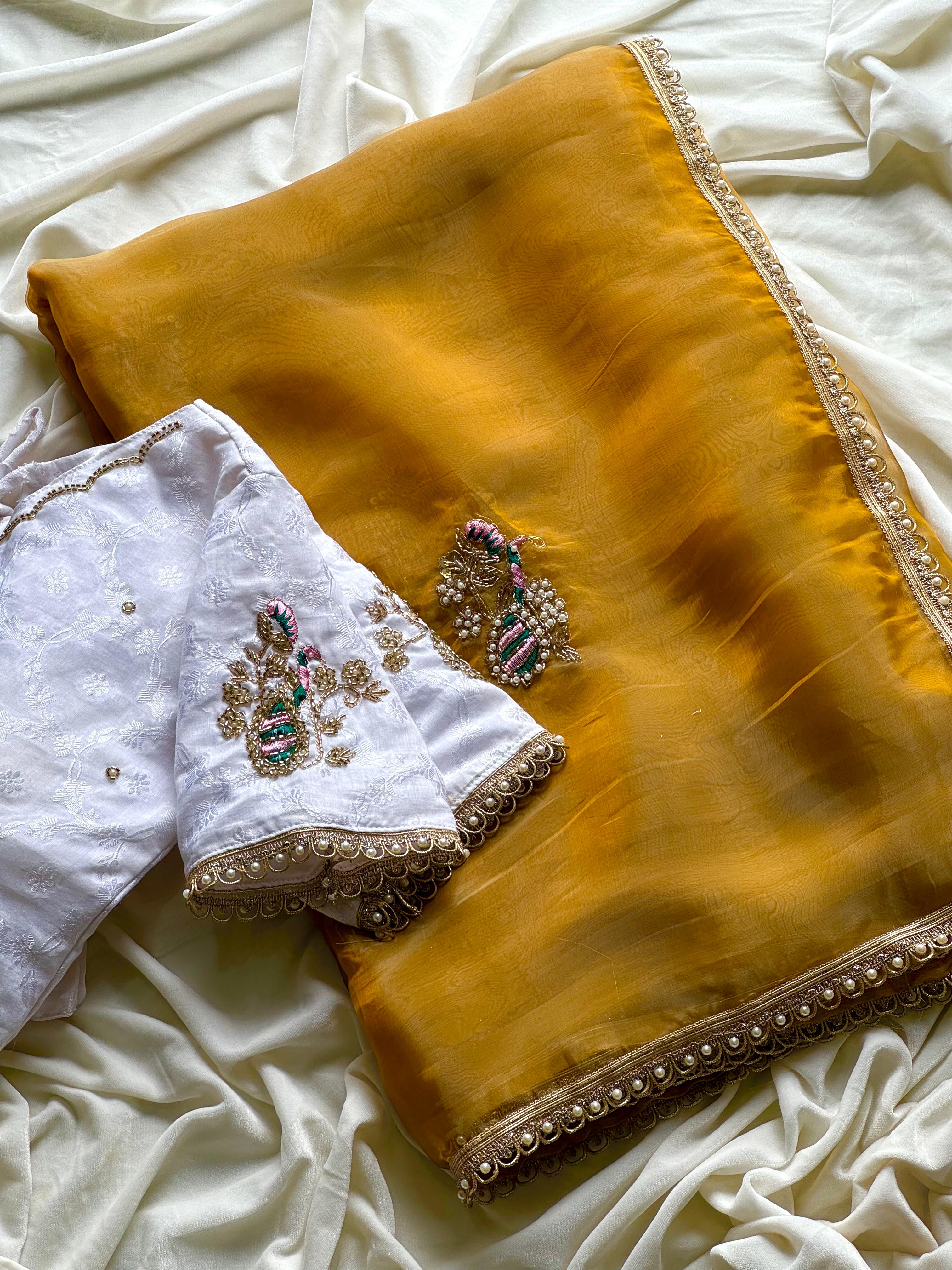 Mustard yellow saree with white blouse on a white fabric background
