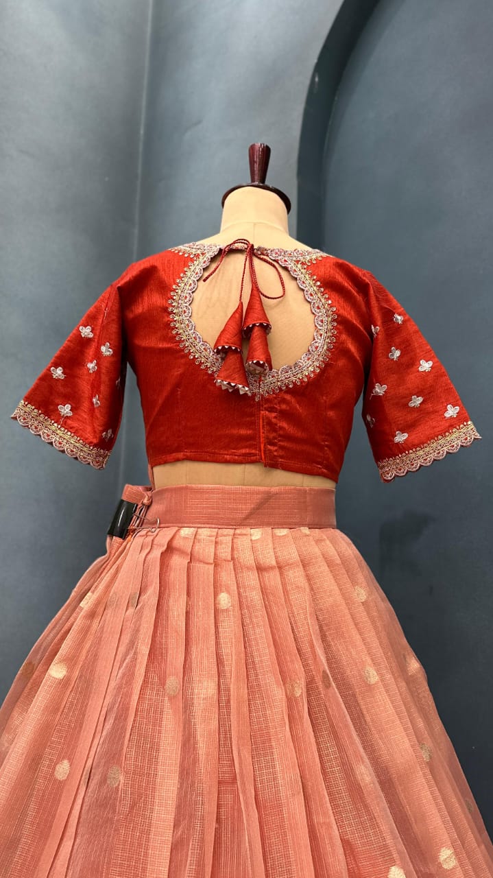 Light orange lehanga with intricate designs on a mannequin against a gray background