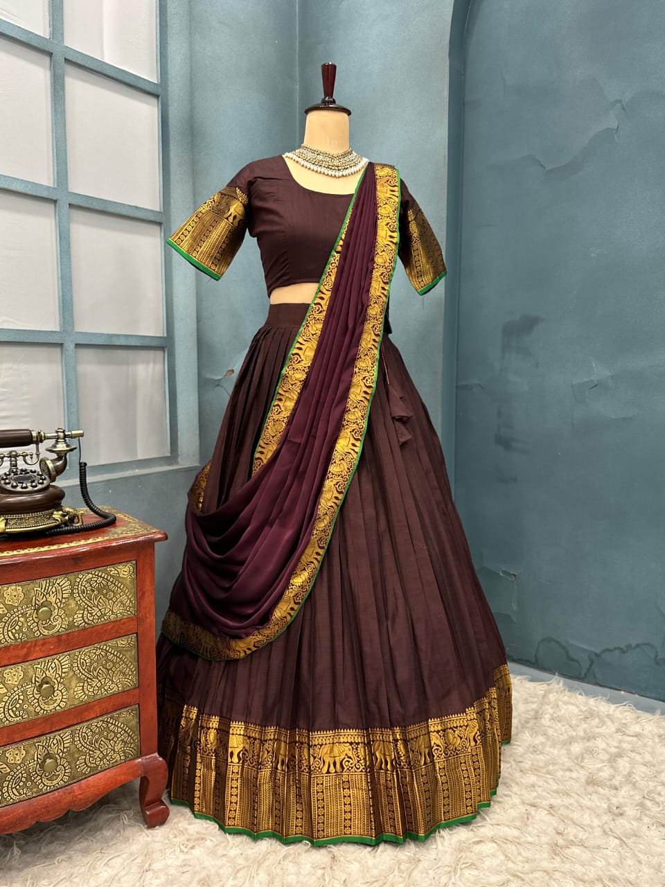 Brown and gold traditional outfit on a mannequin against a blue wall.