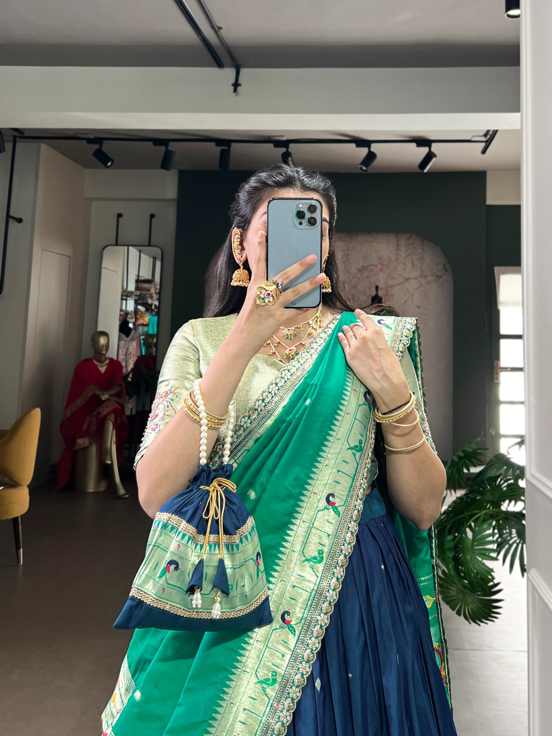 Person wearing a navy blue saree with a matching bag indoors.