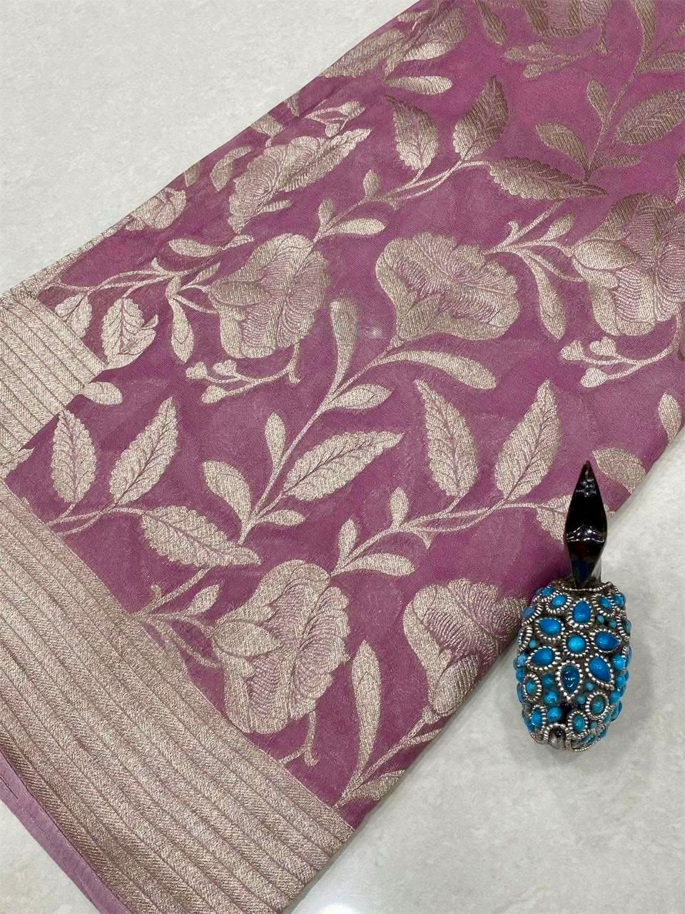 Onion pink fabric with floral pattern and a decorative blue and gold pendant on a white surface