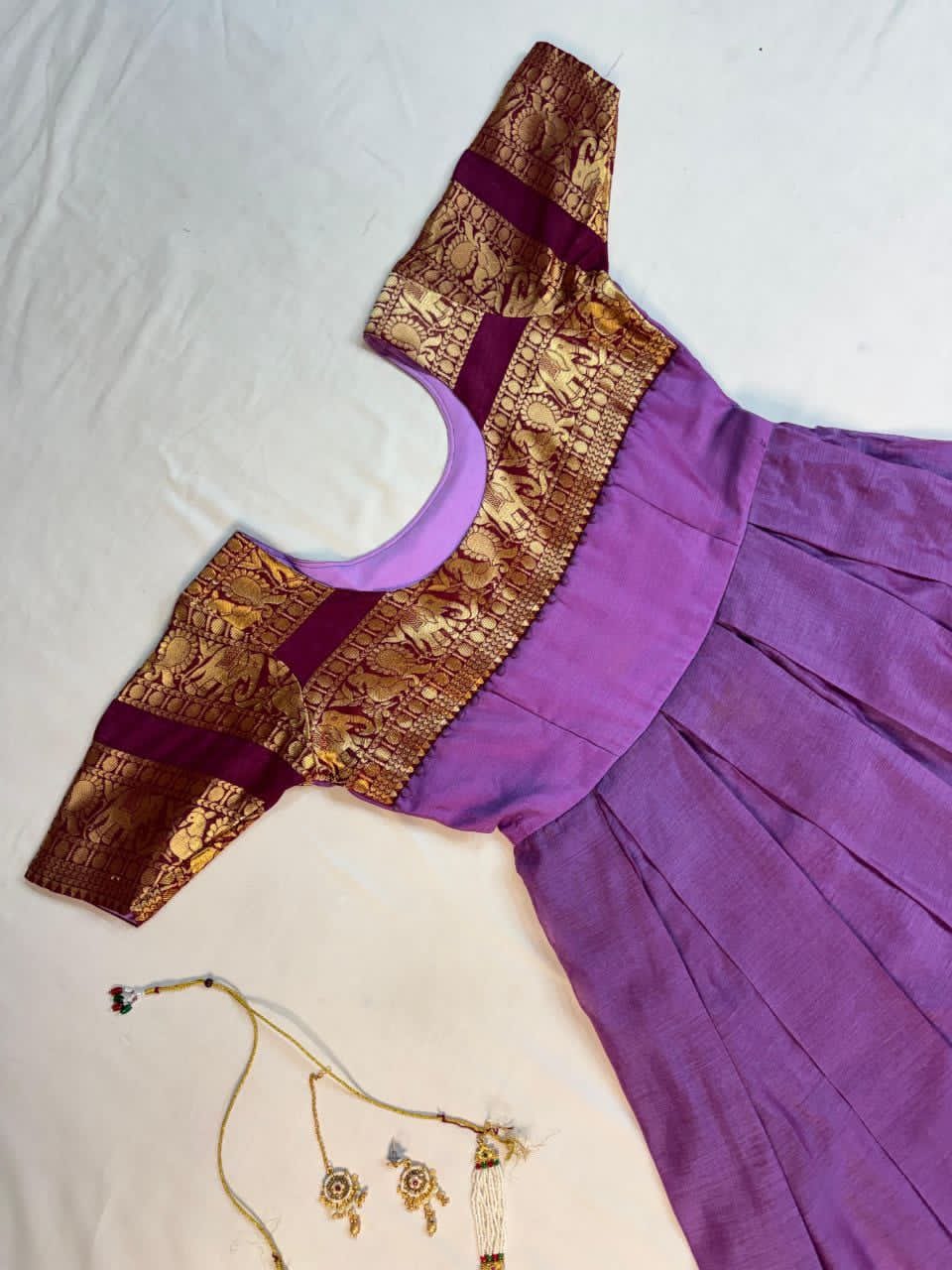 Lavender dress with gold blouse and jewelry on a white background