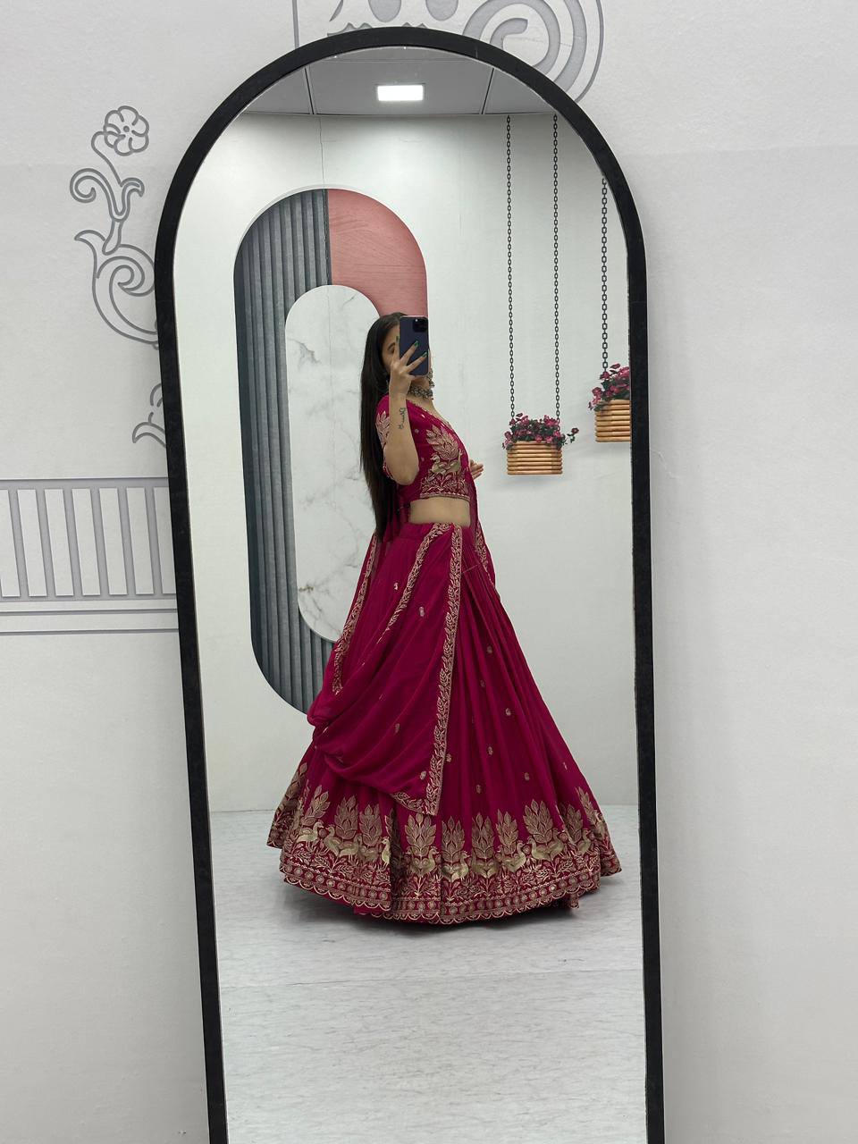 Person wearing a pink traditional outfit standing in front of a full-length mirror.