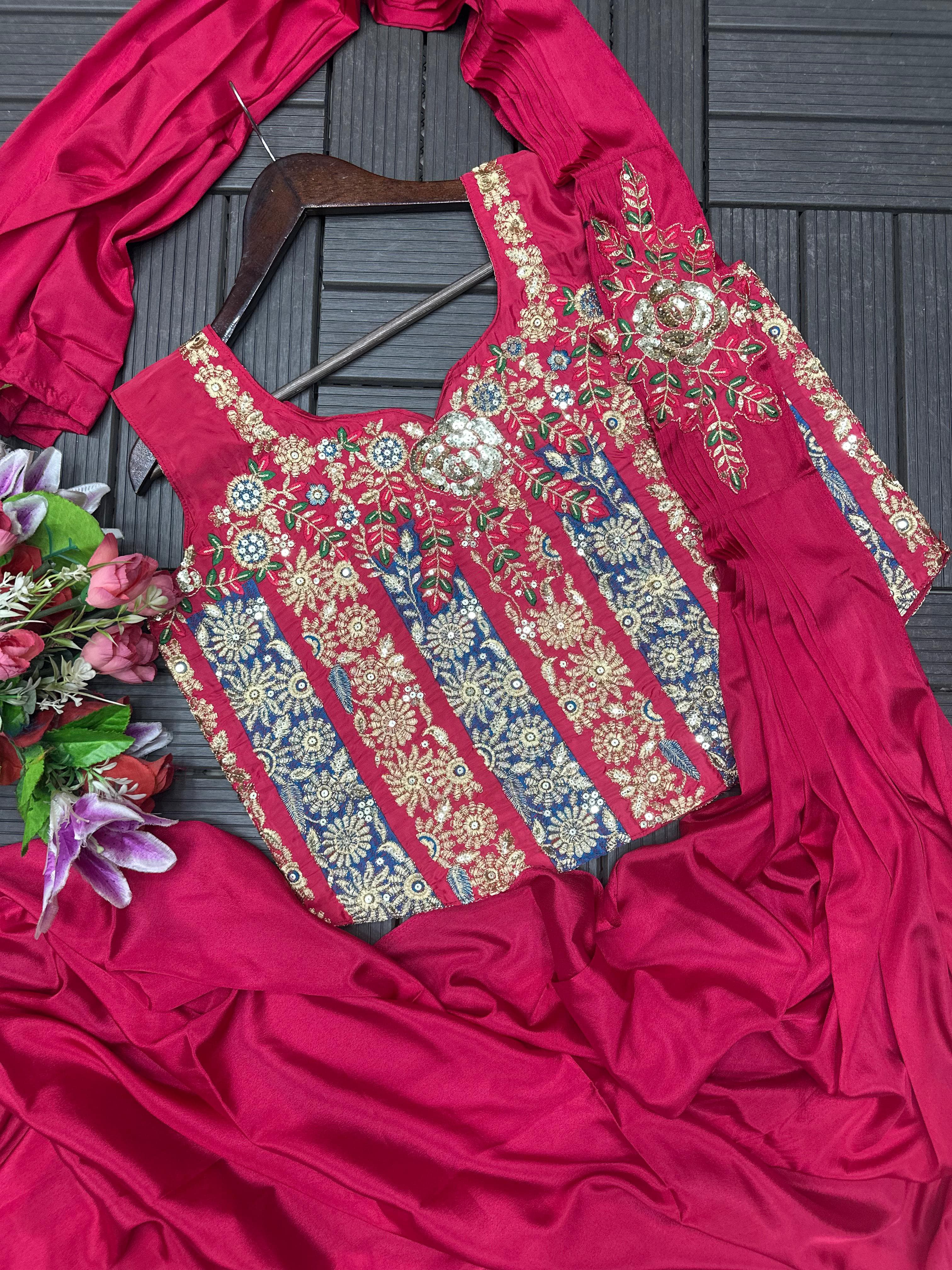Pink embroiderey saree and blouse on a wooden hanger with a fabric and flowers in the background