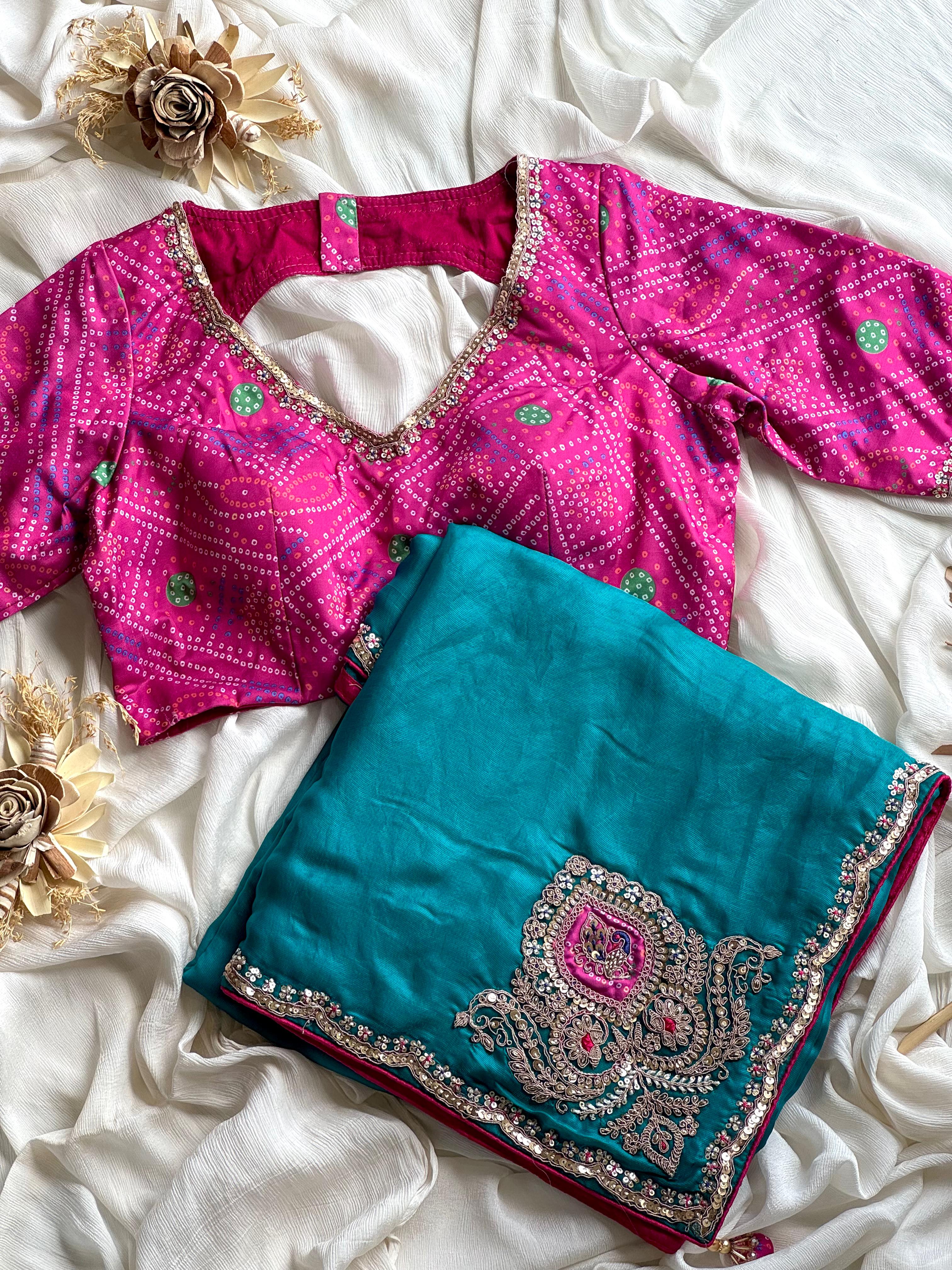 Pink blouse with floral patterns and a teal blue saree with intricate designs on a white fabric background.