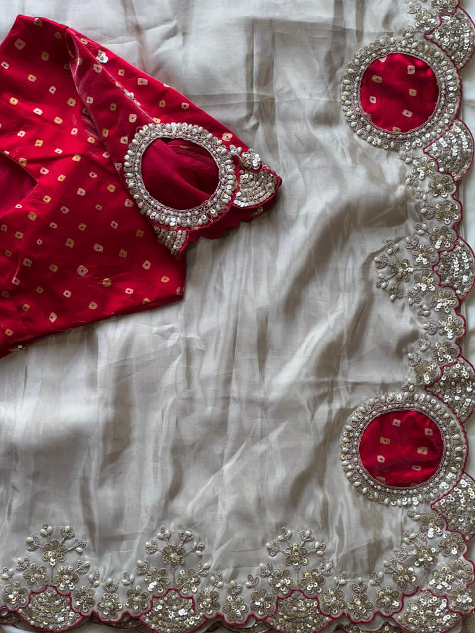 Red blouse with white saree featuring intricate silver and red embroidery