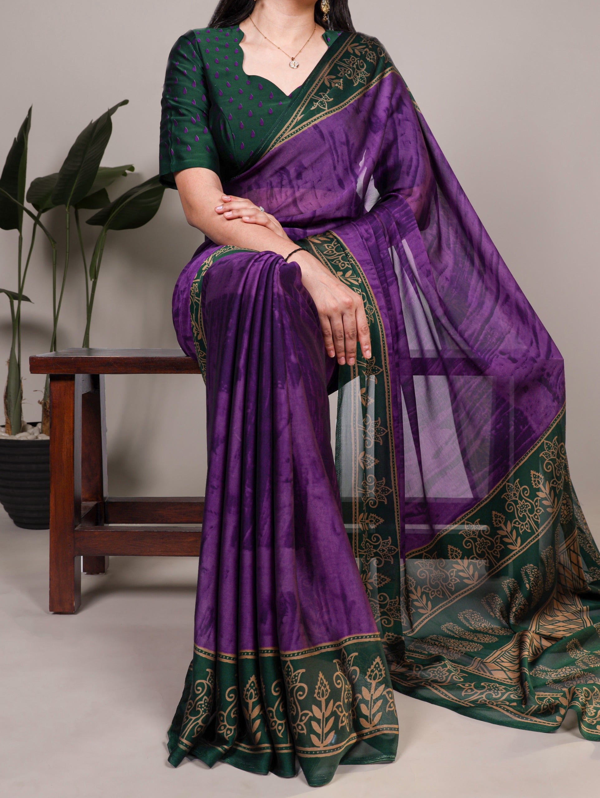 Woman wearing a purple and saree with a plant in the background