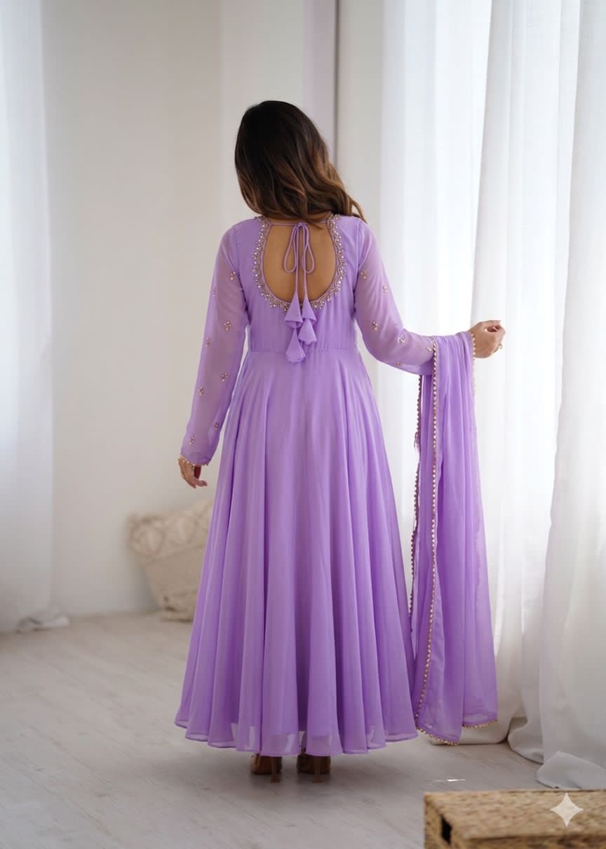 Woman wearing a long purple dress with a matching scarf in a bright room.