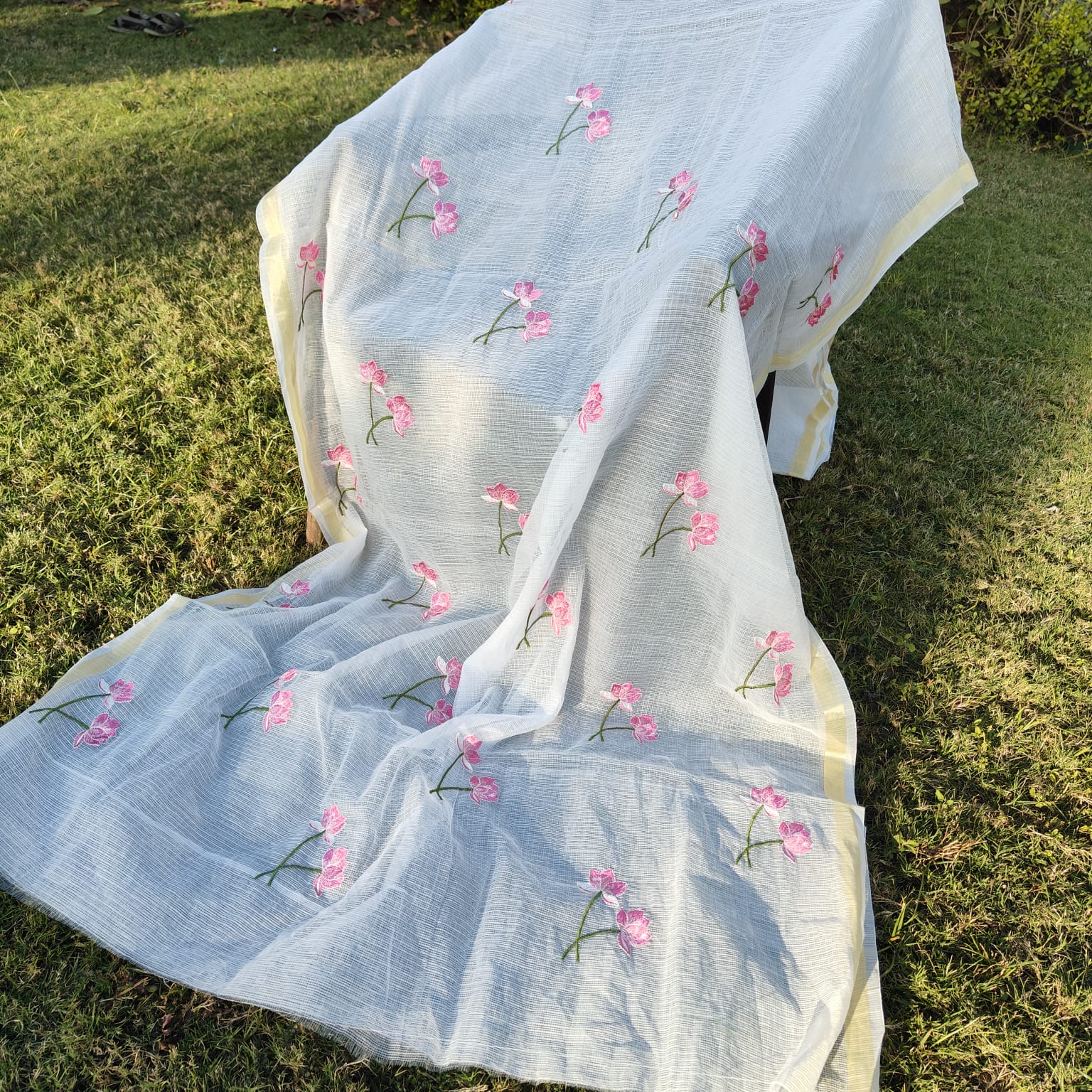 White fabric with  floral embroidery on a grassy background