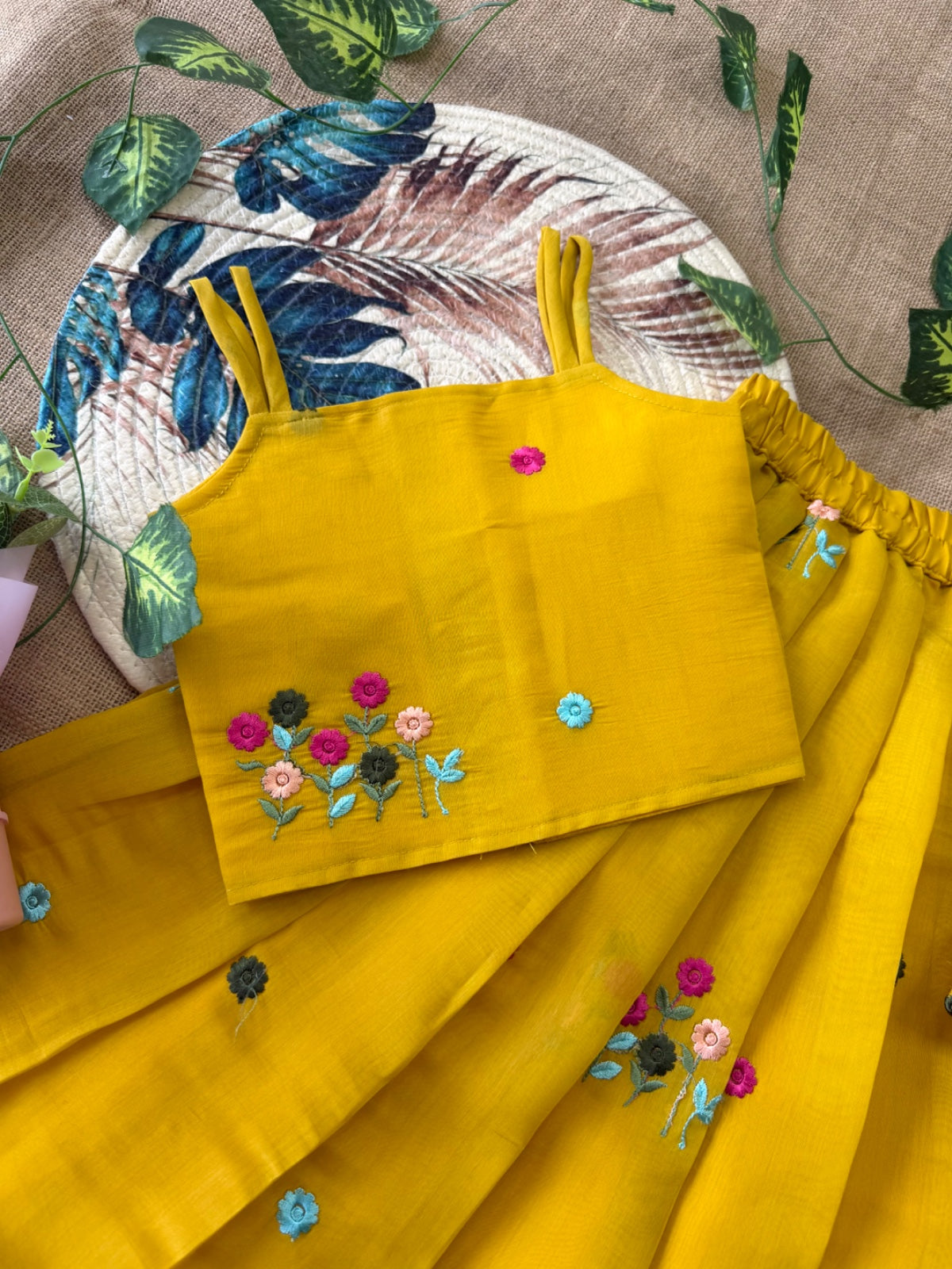 Mustard Yellow embroidered top and skirt set on a textured surface with decorative elements.