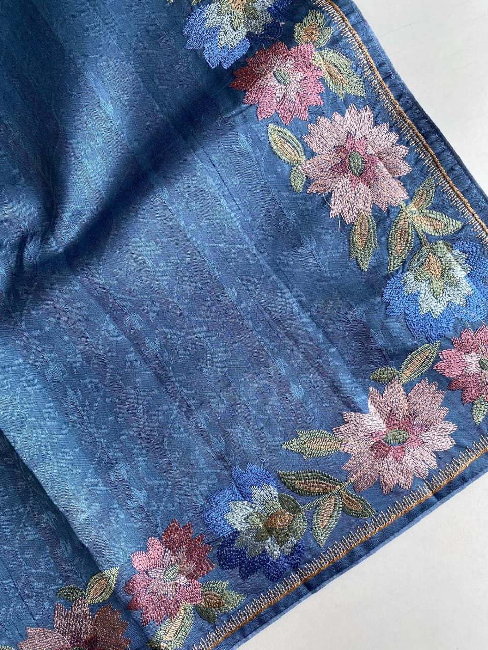 Blue fabric with floral embroidery on a white background
