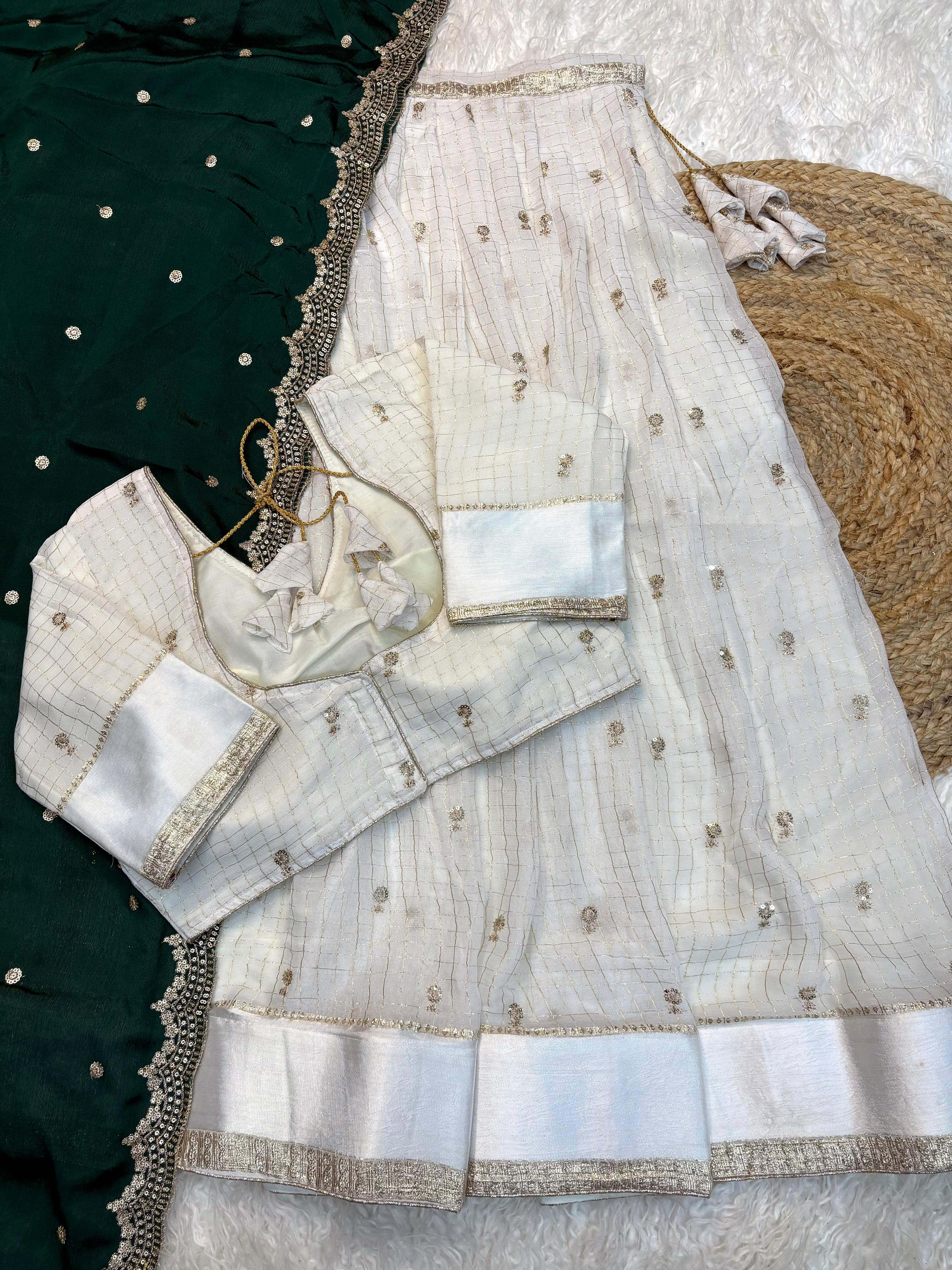 White embroidered blouse with dark green traditional outfit with gold details on a textured surface