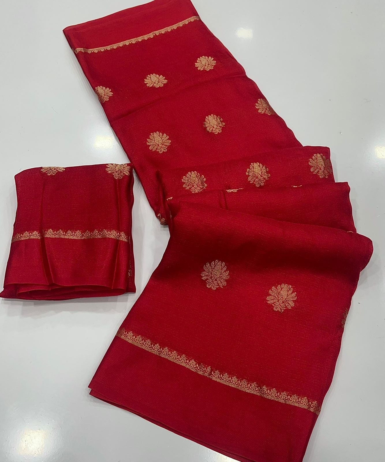 Red saree with gold patterns on a white background