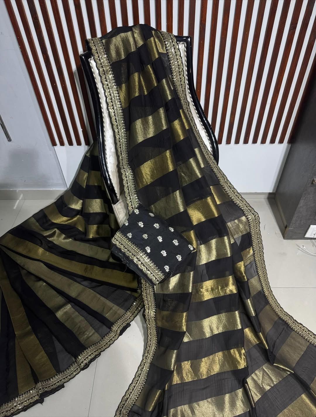 Black and gold stripe fabric with a patterne corner on a white floor.