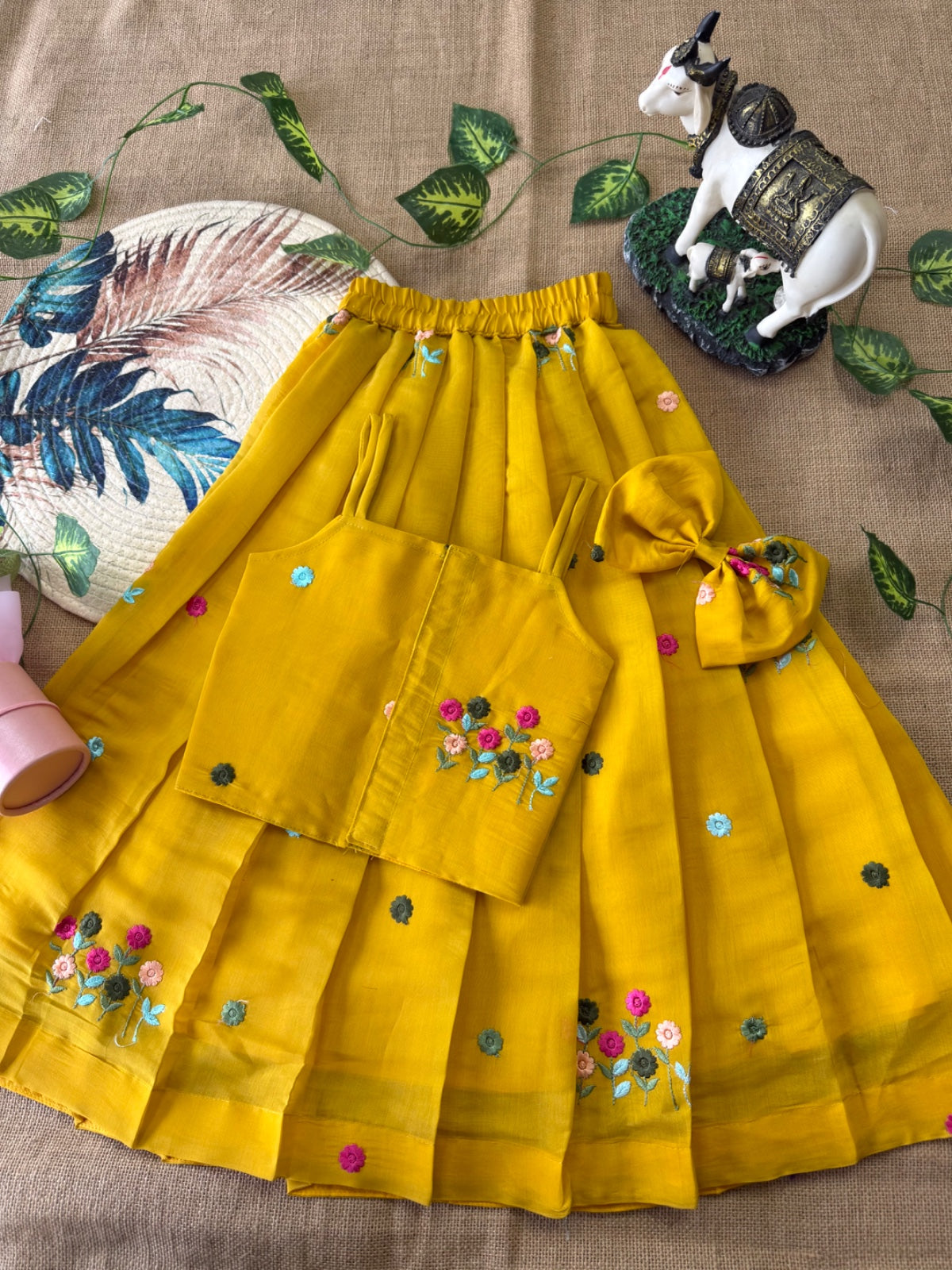 Mustard Yellow traditional outfit with floral embroidery on a textured surface