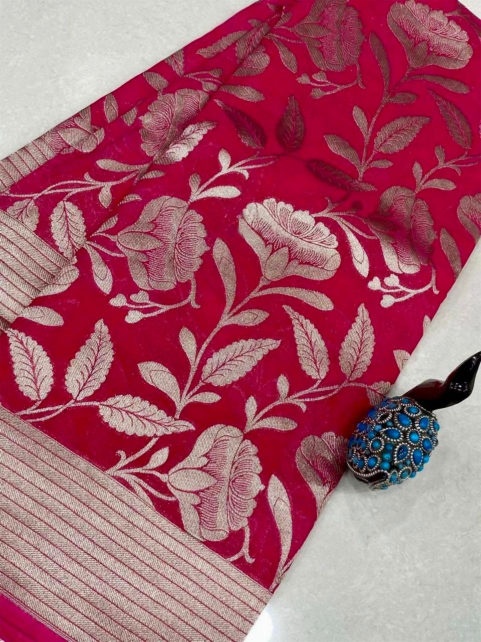 Vibrant Pink floral pattern fabric with a decorative brooch on a white background