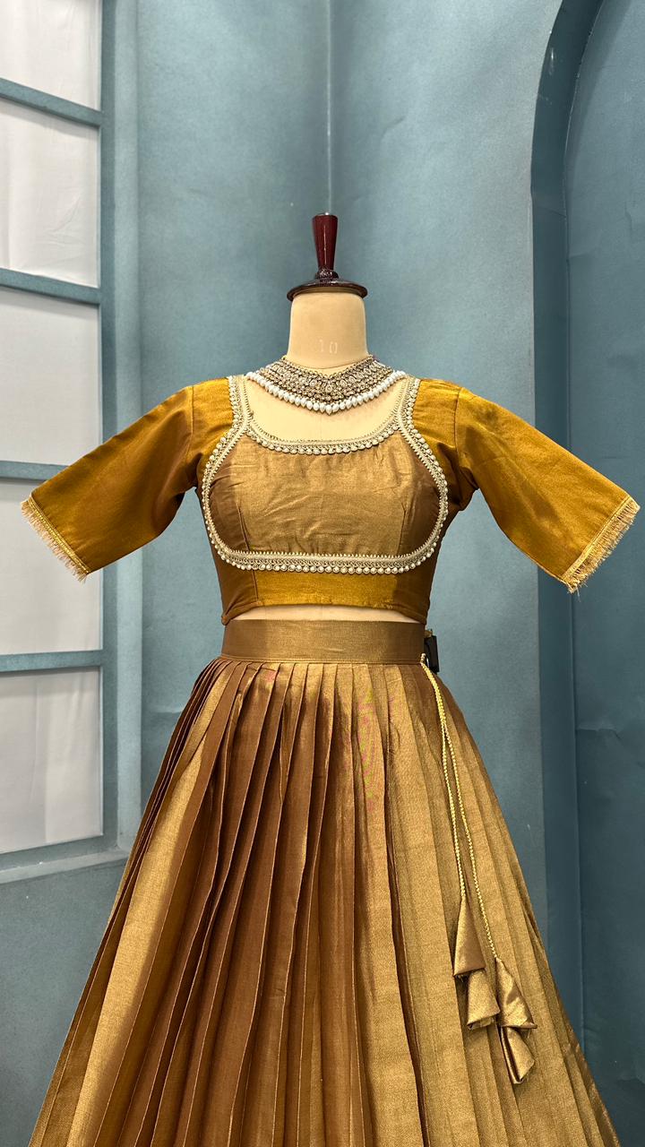 Gold and brown dress with intricate detailing on a mannequin against a light blue wall.
