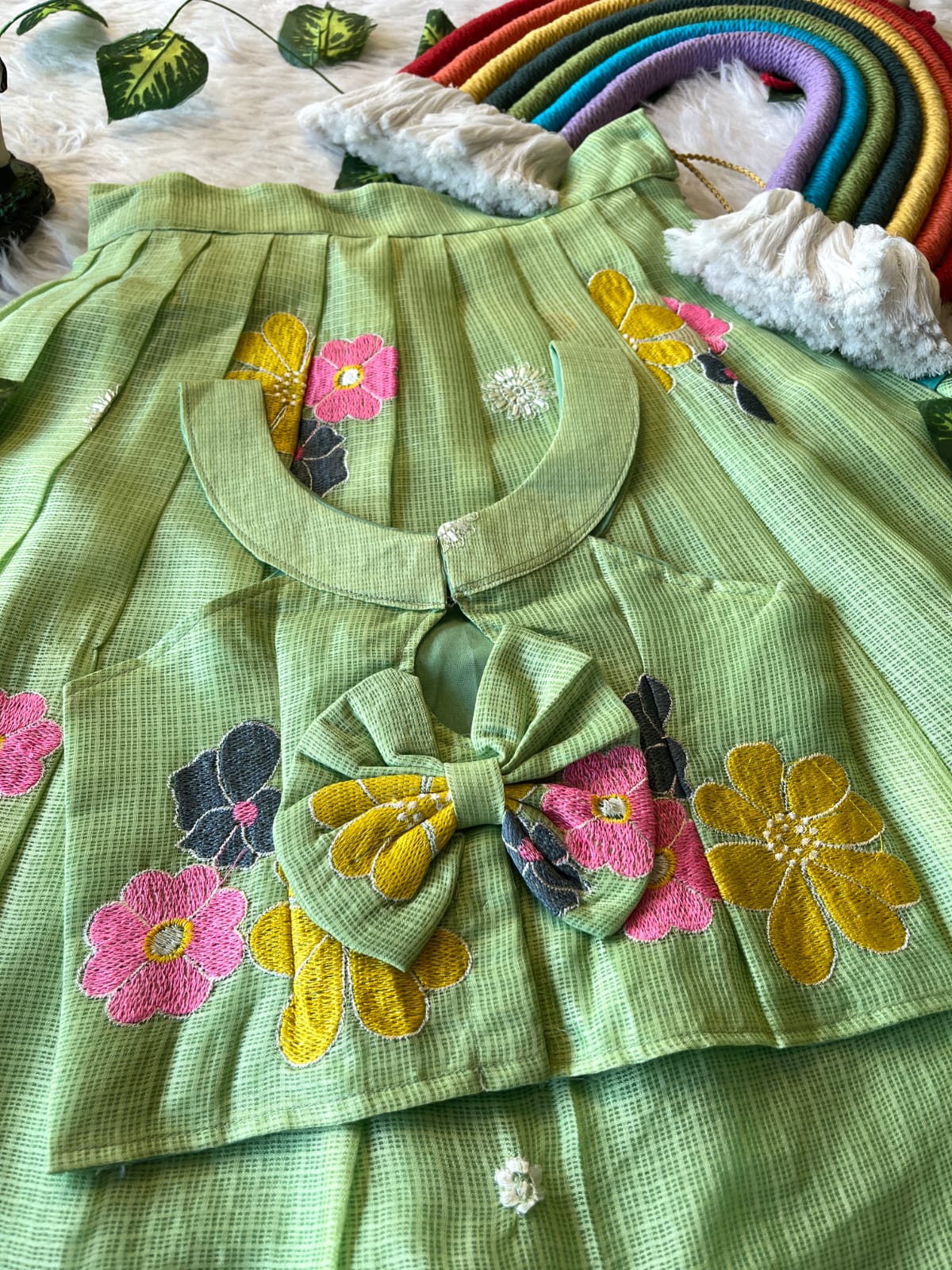 Pista dress with floral and butterfly appliqués on a textured surface.