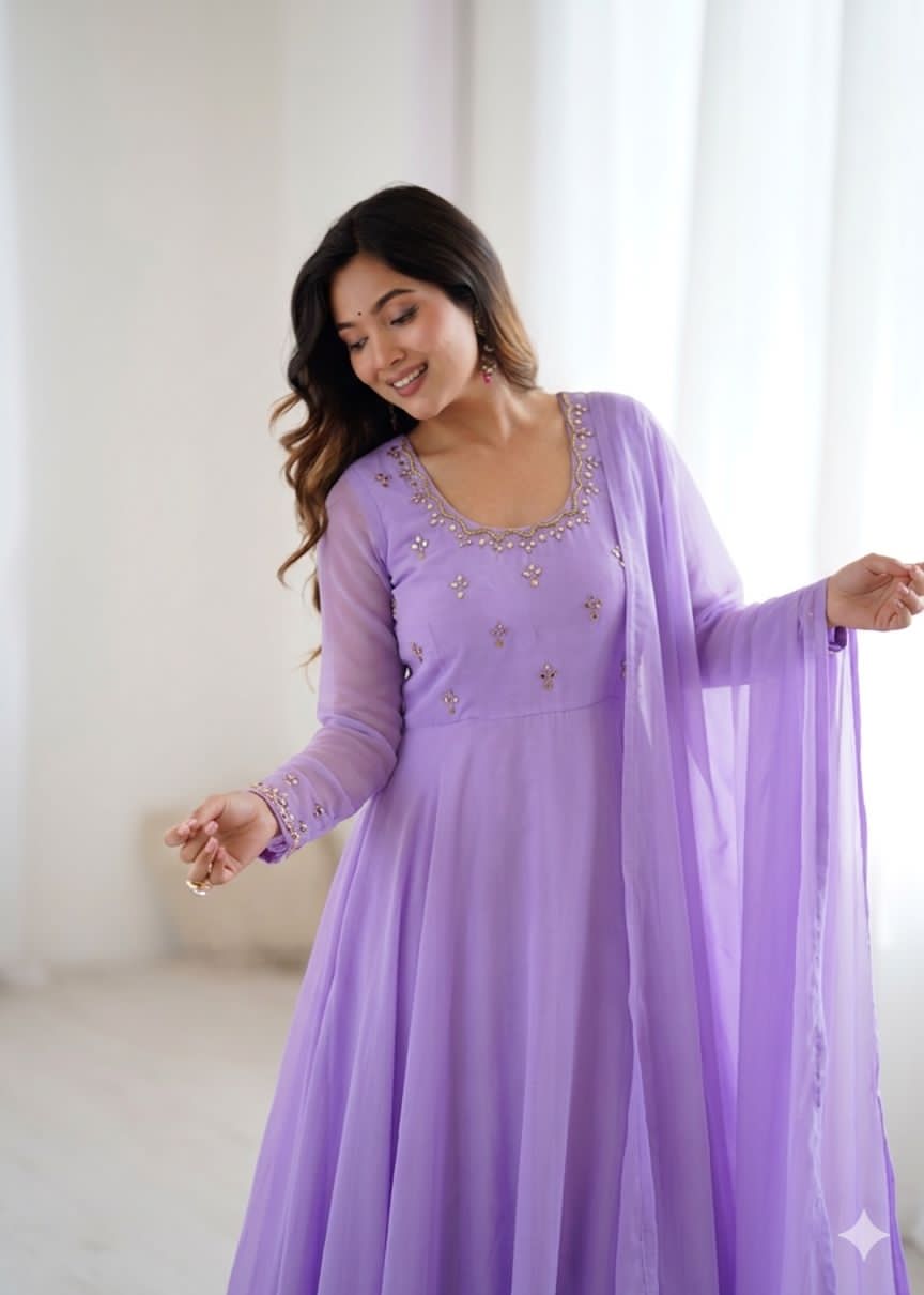 Woman wearing a purple gown with intricate designs in a bright room.