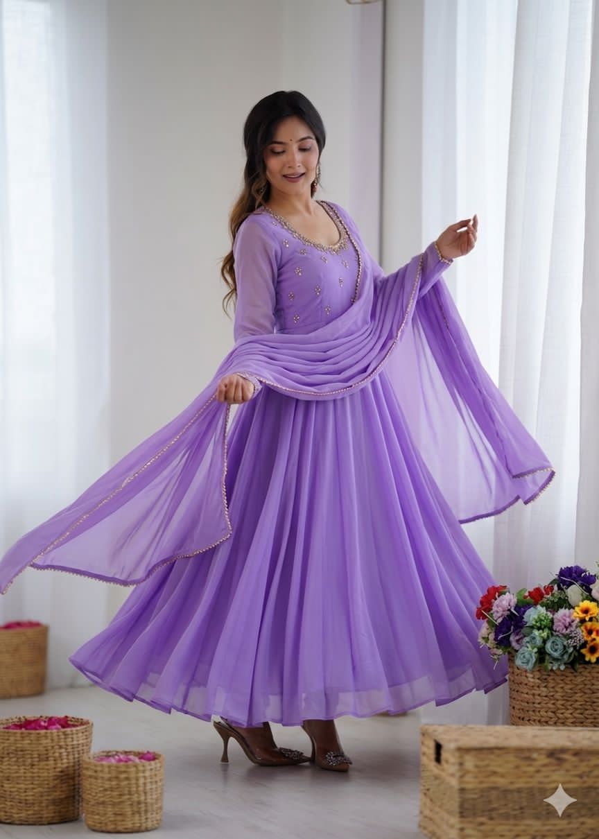 Woman wearing a purple dress with a sheer dupatta in a bright room.
