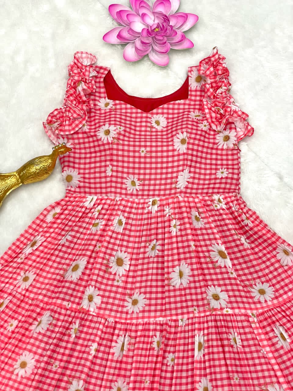 Peach checkered dress with flower accessory on a white background