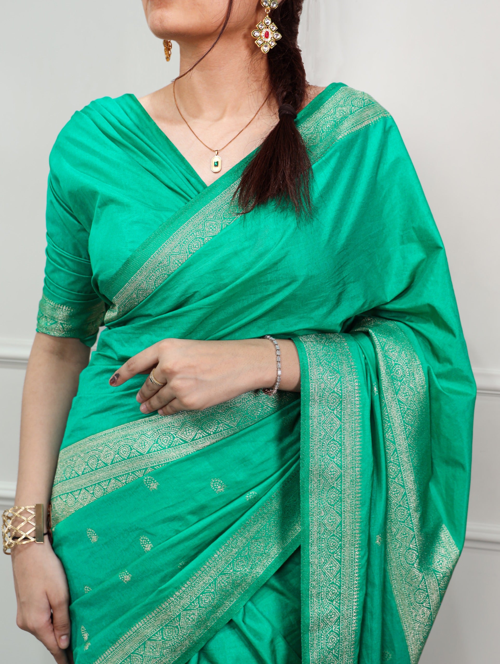 Cyan saree with gold border worn by a person against a white background
