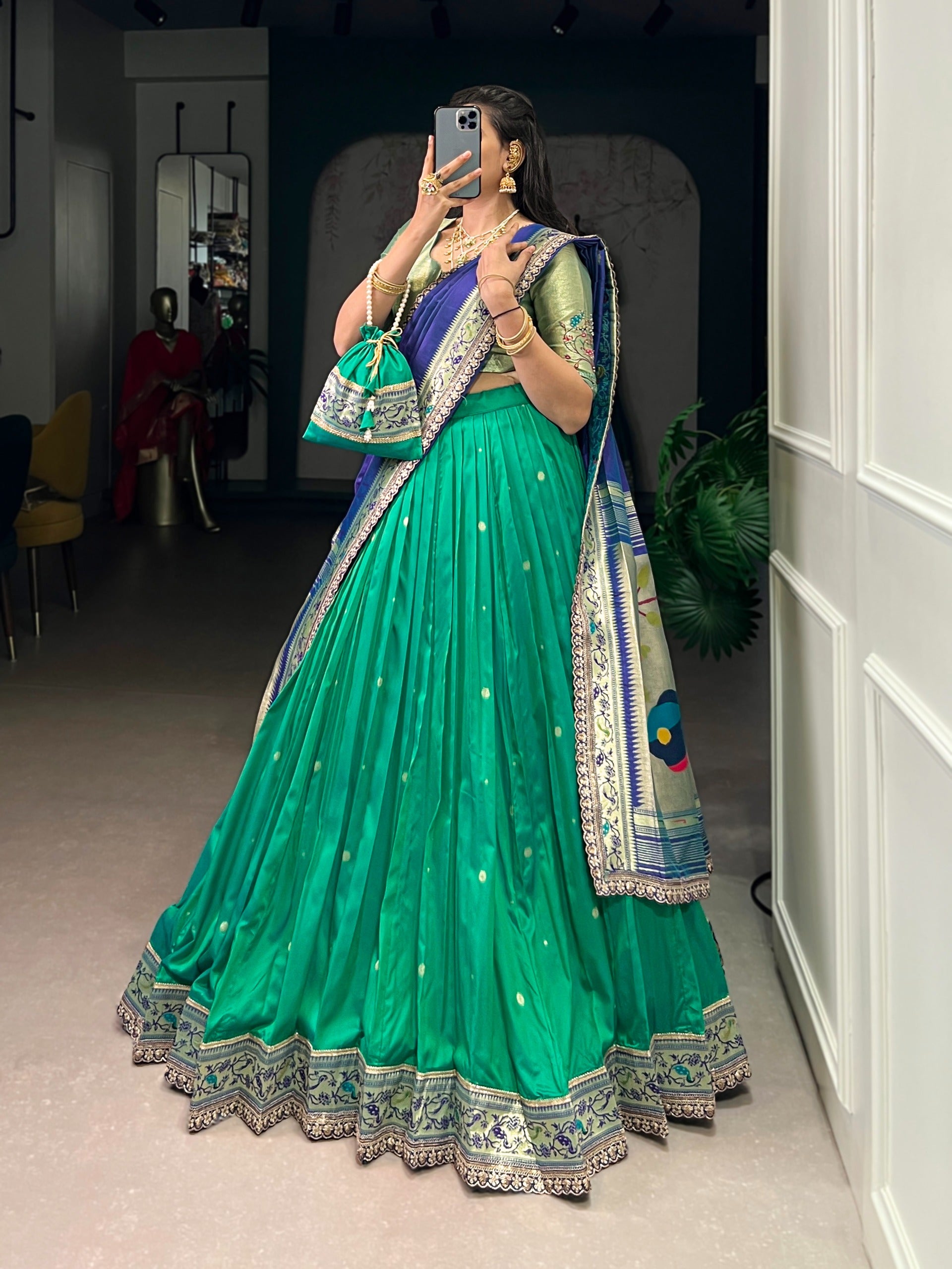 Person wearing a cyan traditional outfit with a matching bag indoors.