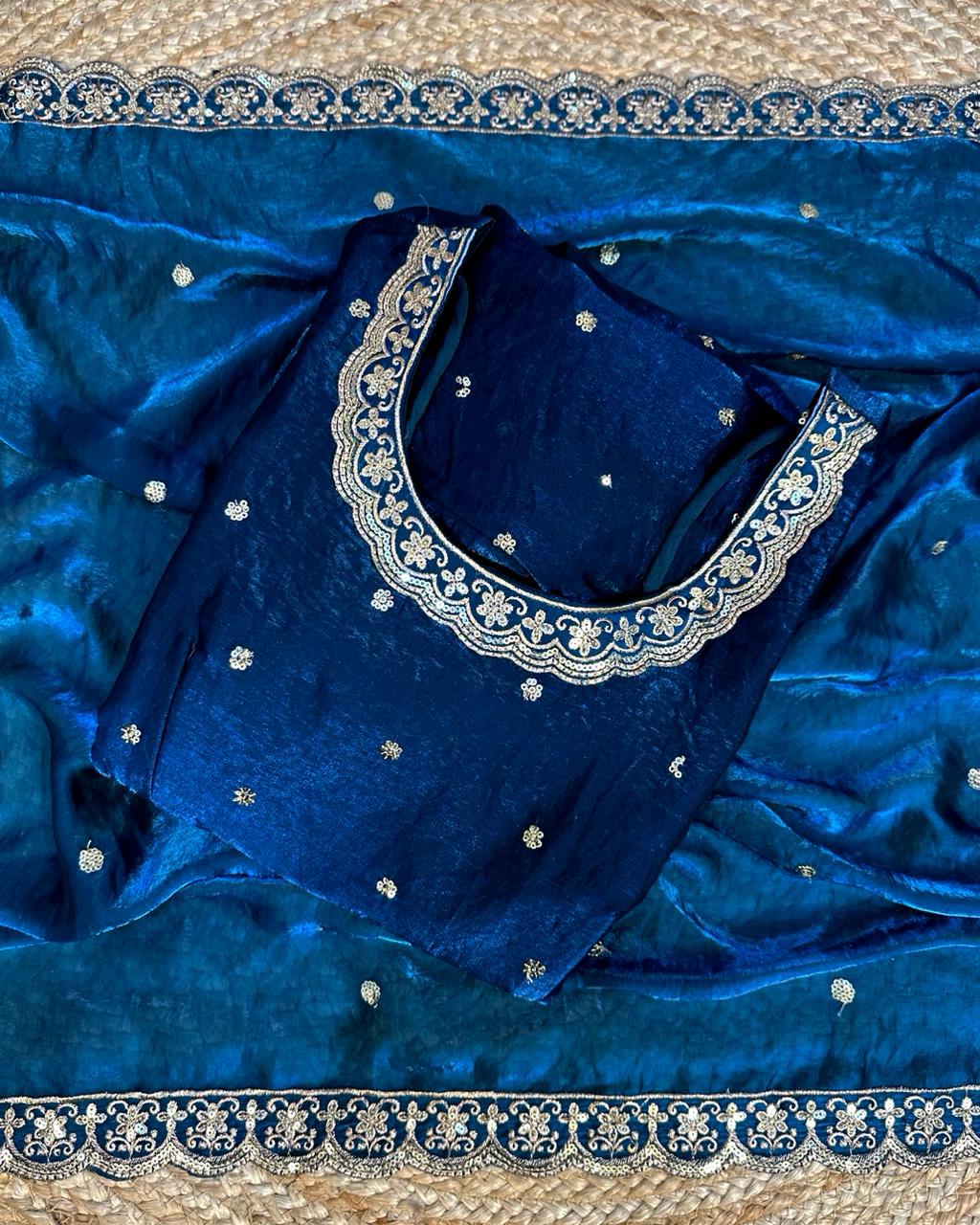 Teal Blue fabric with intricate white embroidery on a textured surface