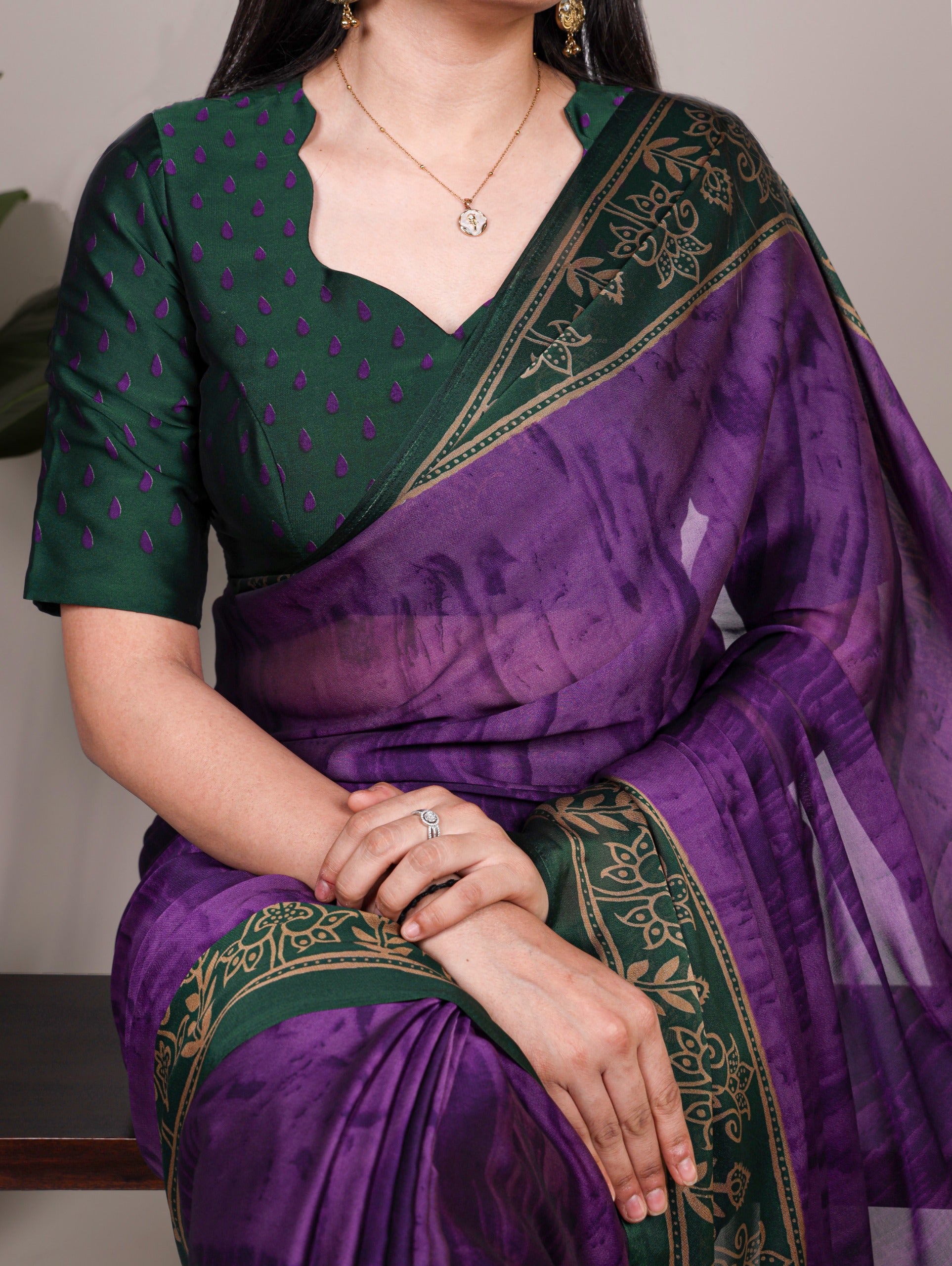 Woman wearing a and purple saree with intricate patterns.