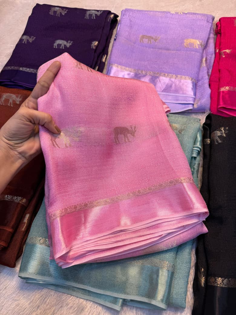Stack of colorful sarees with a hand holding a baby pink one.