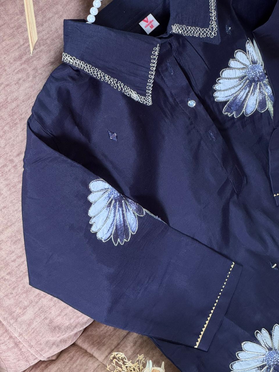 Navy blue shirt with floral embroidery on a pink fabric background