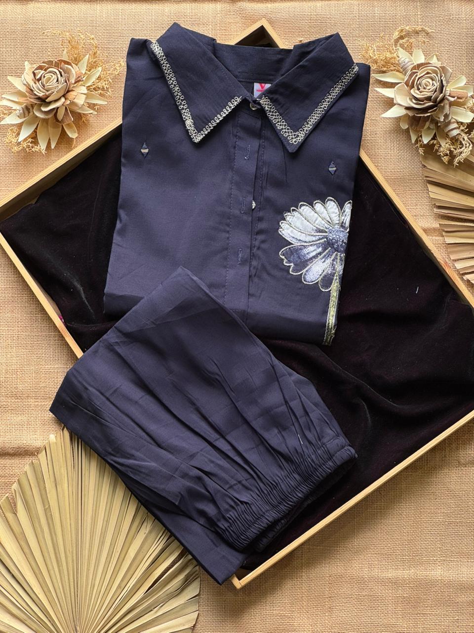 Navy blue shirt and shorts set in a box on a decorative background with flowers.