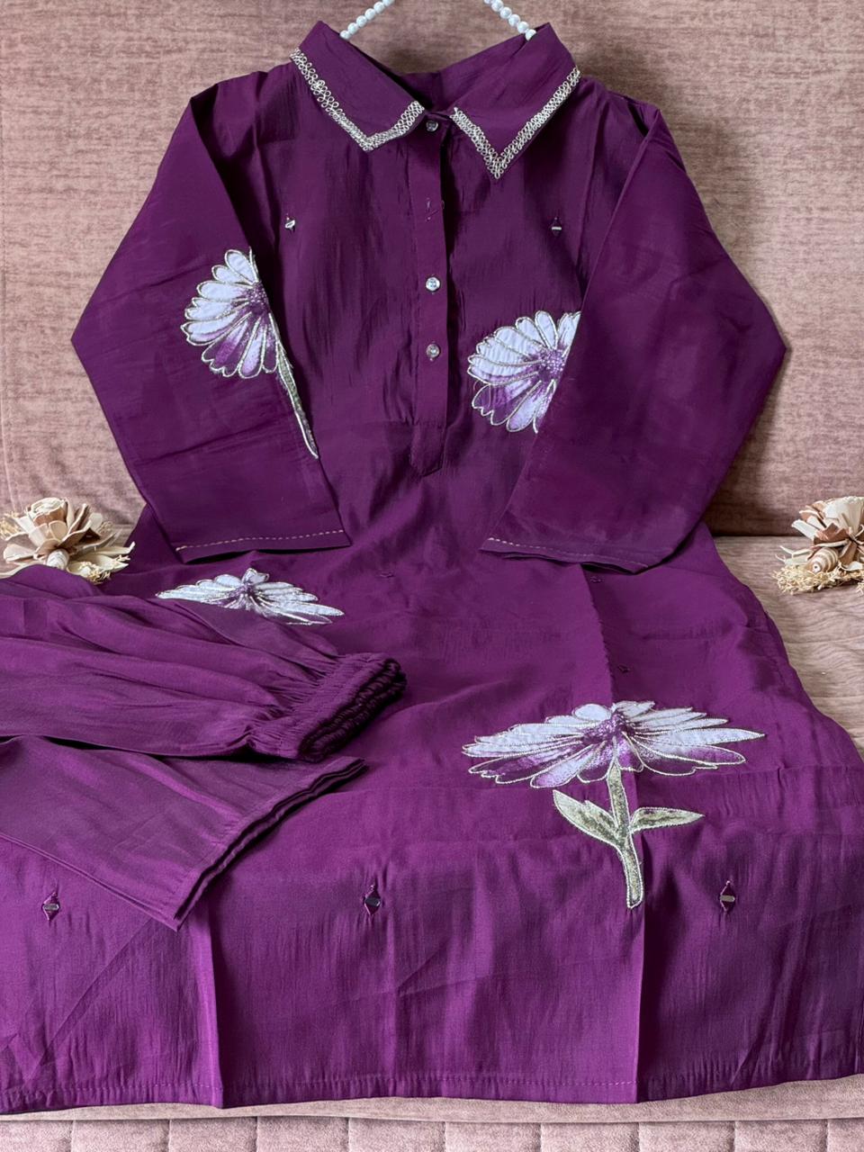 Purple shirt with floral embroidery on a wooden surface