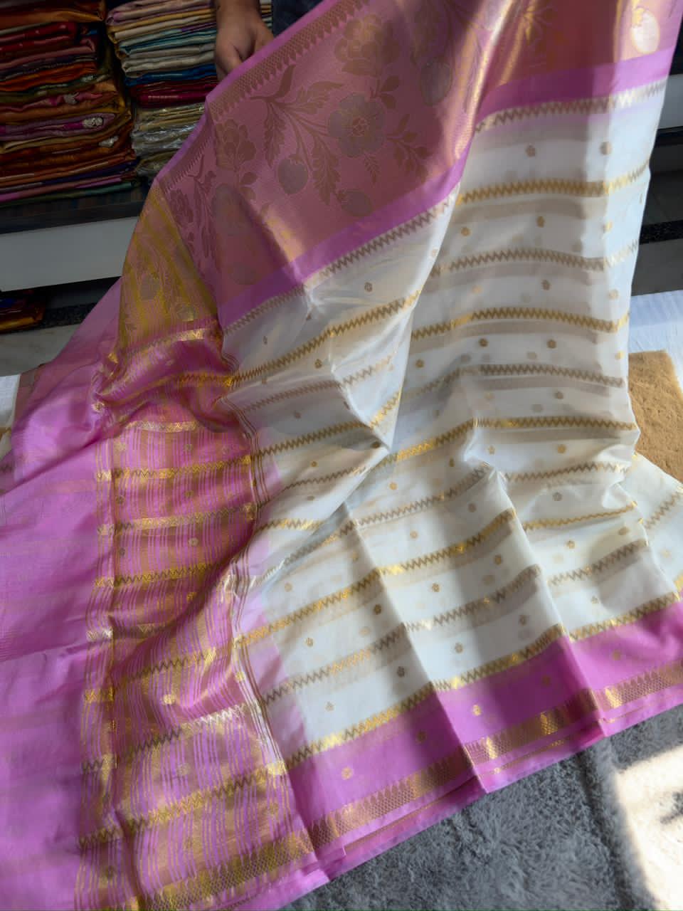 Baby Pink and white saree with gold patterns on a texture surface