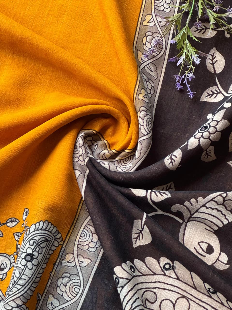 Close-up of yellow fabric with a black and white patterned fabric in the background.