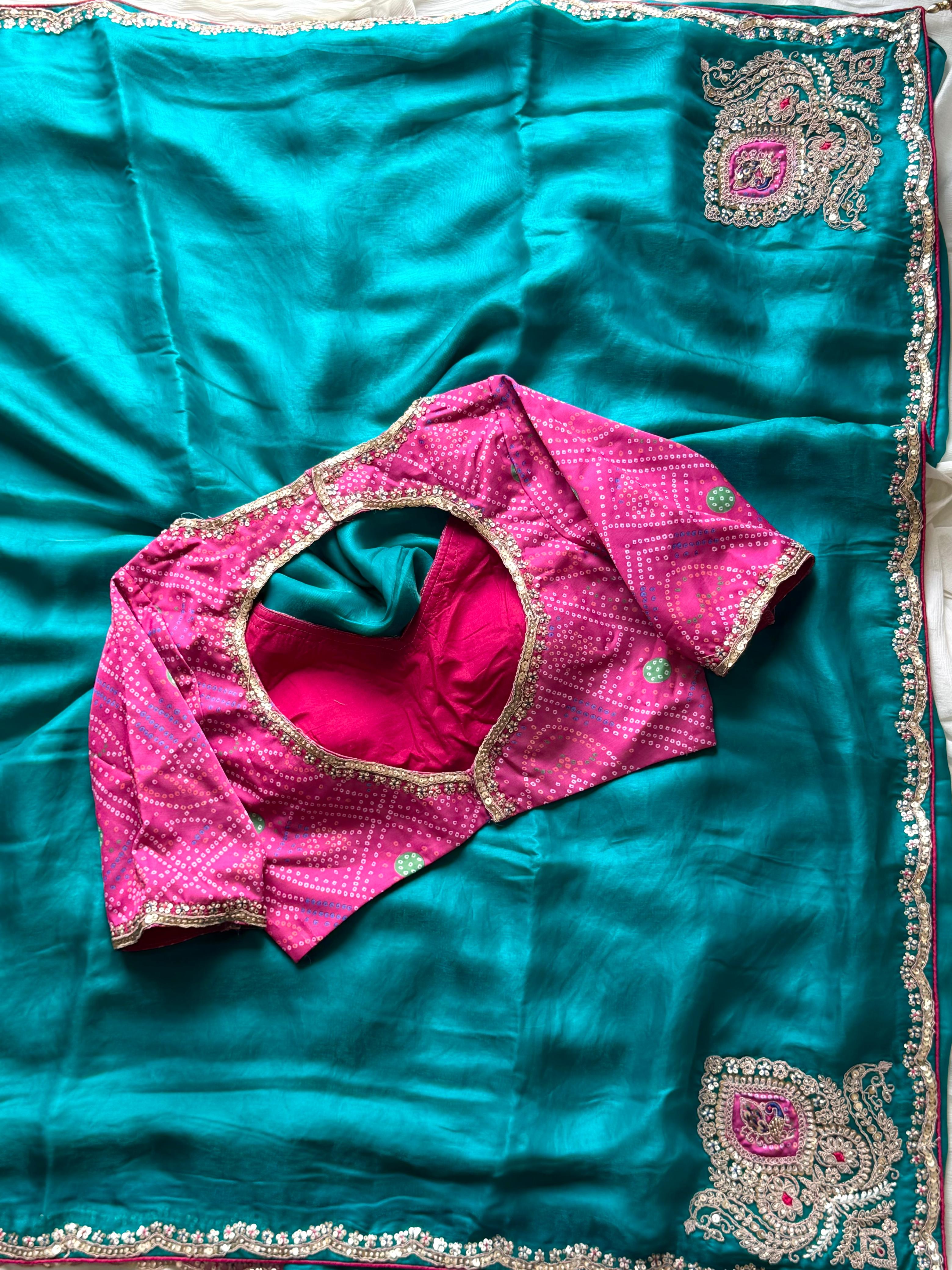 Teal blue saree with pink blouse on a matching fabric background
