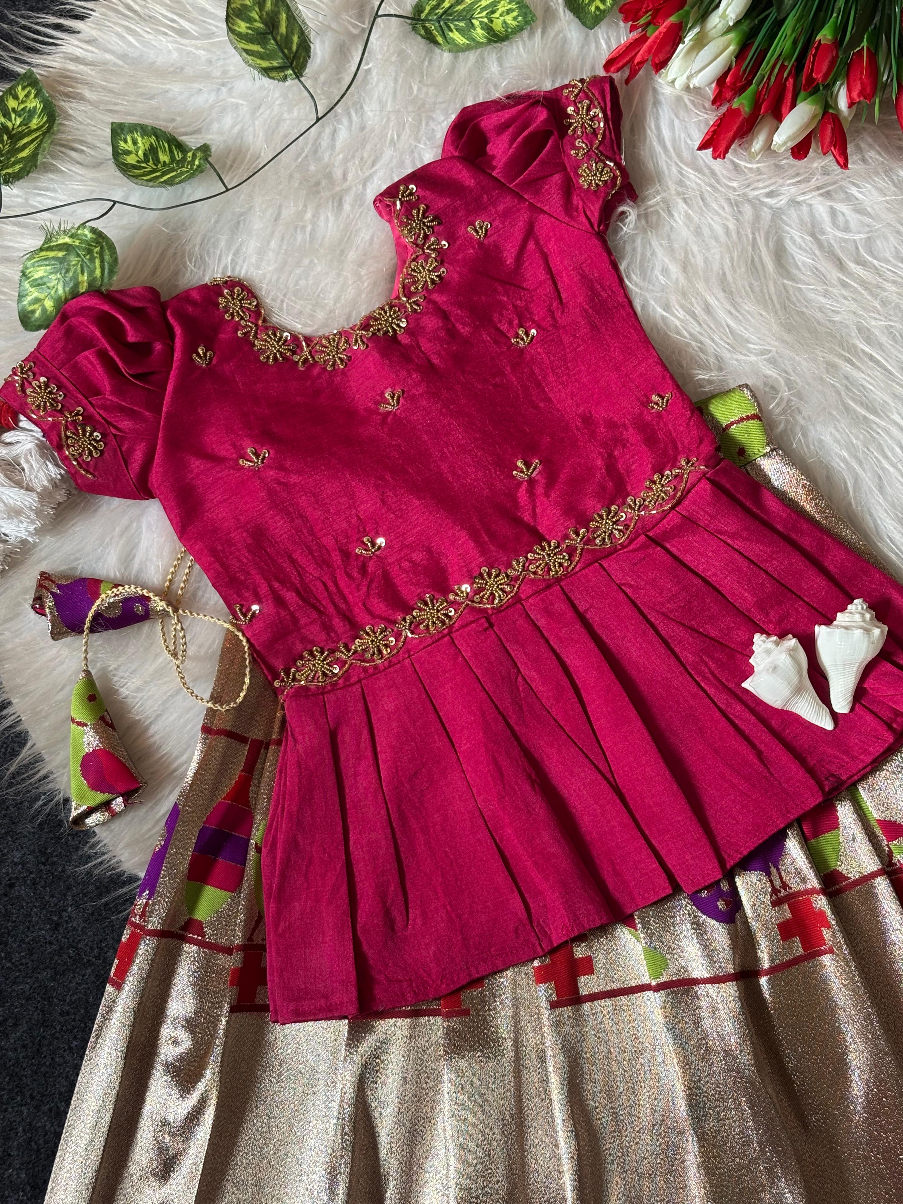 Rani Pink embroidered dress with gold details on a textured surface with decorative elements.