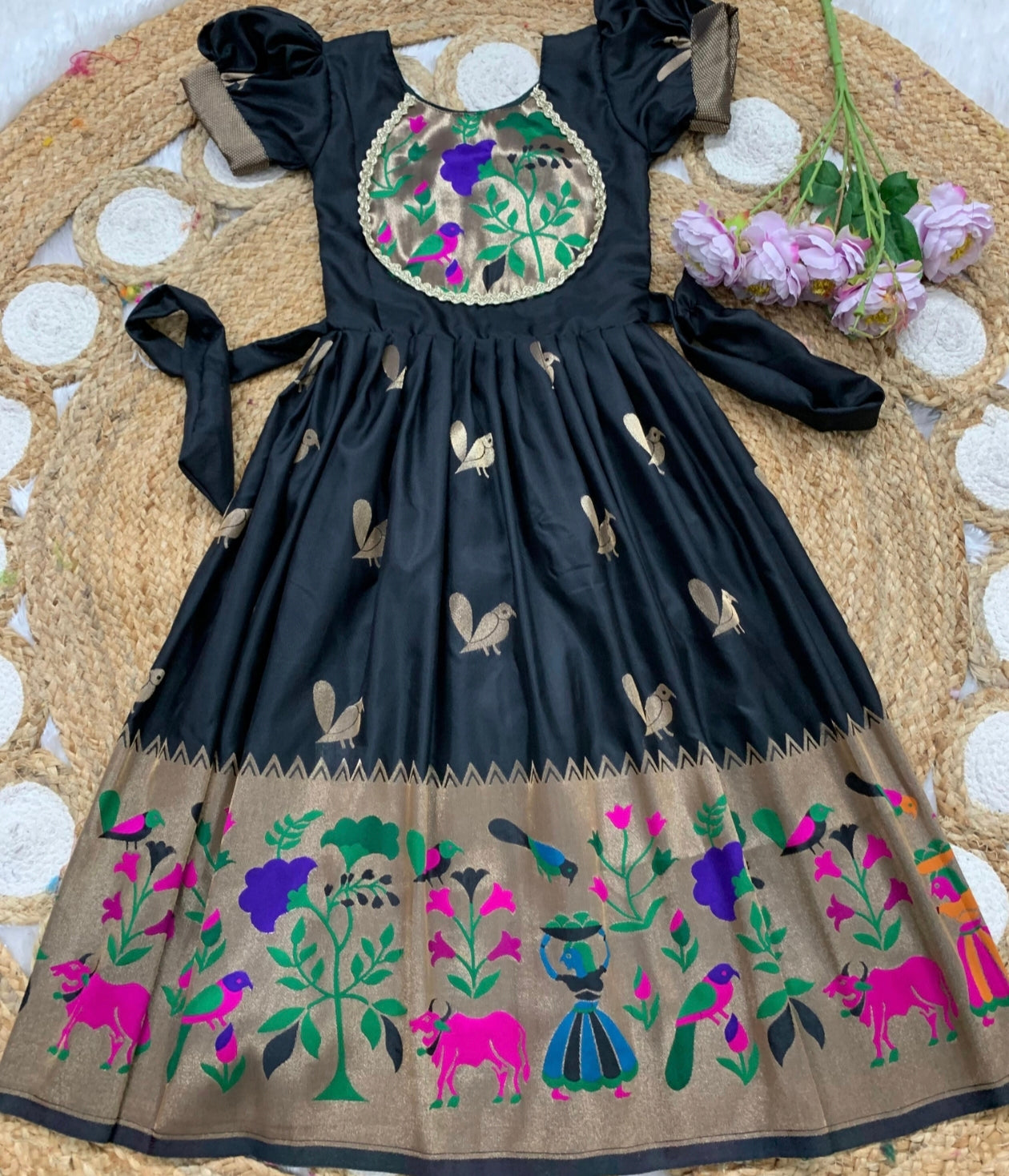 Black dress with colorful floral and animal patterns on a texture surface.